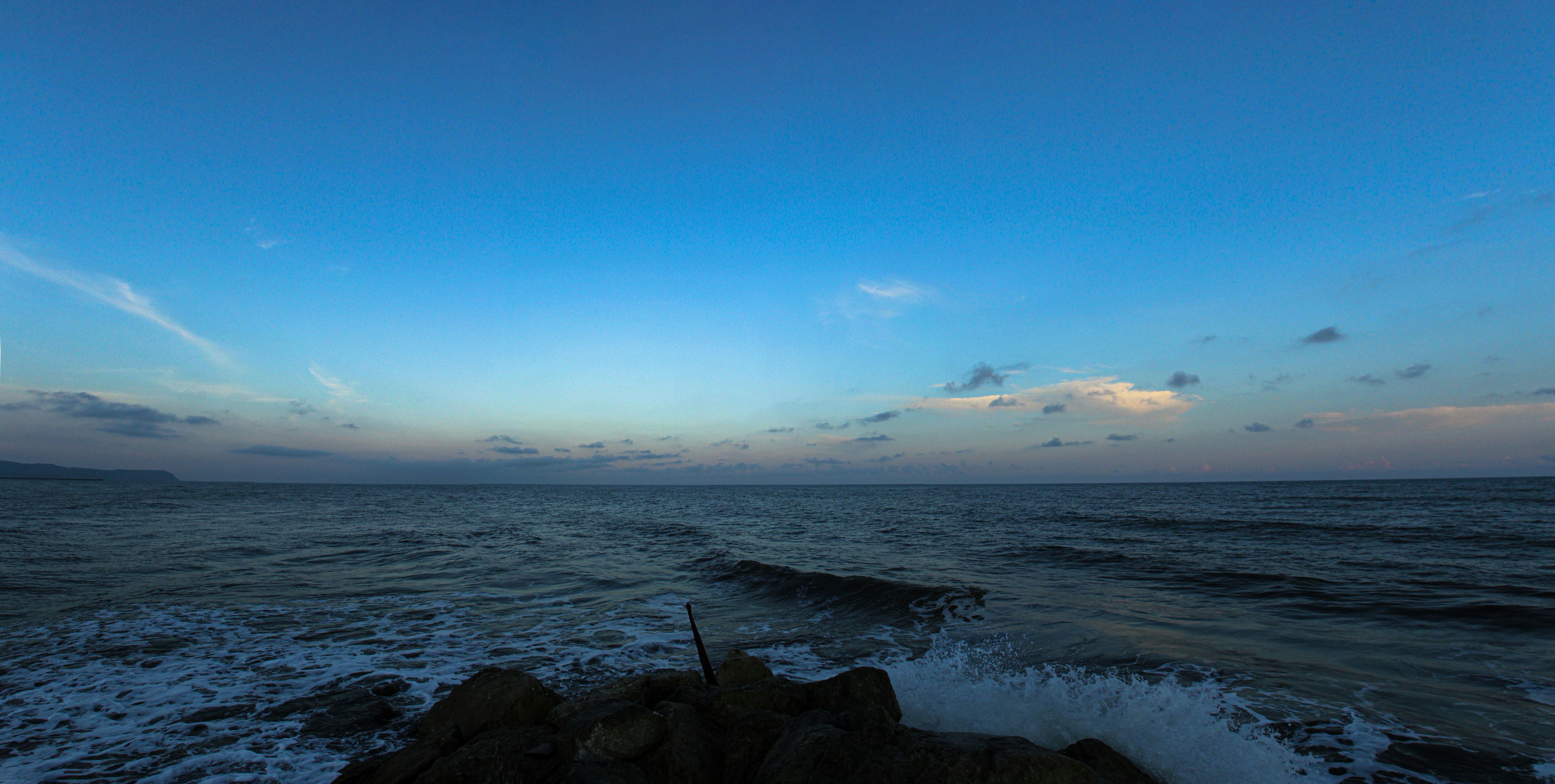 Olas rompiendo sobre las rocas bajo un vasto cielo azul