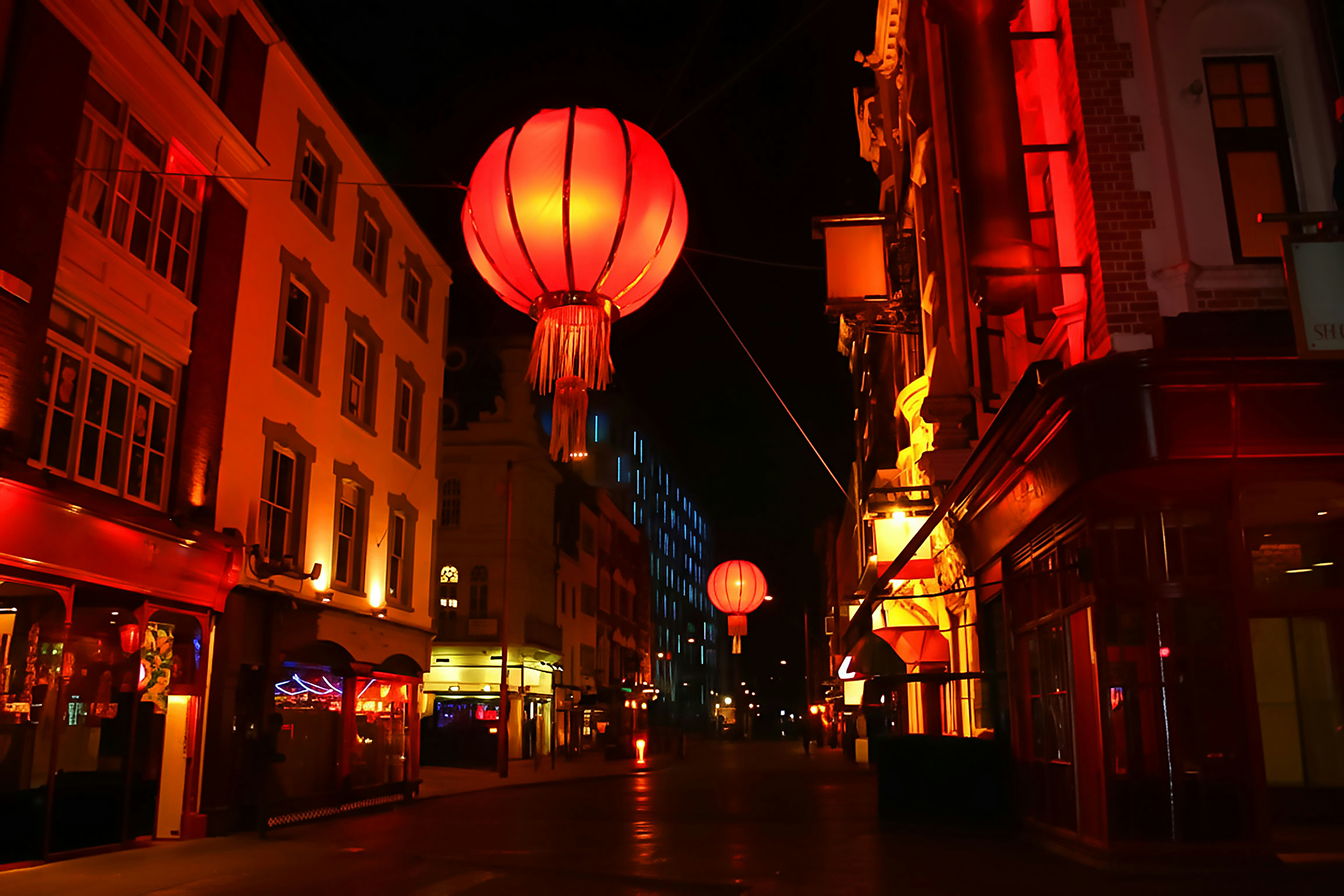 Red lanterns illuminate a city street at night.