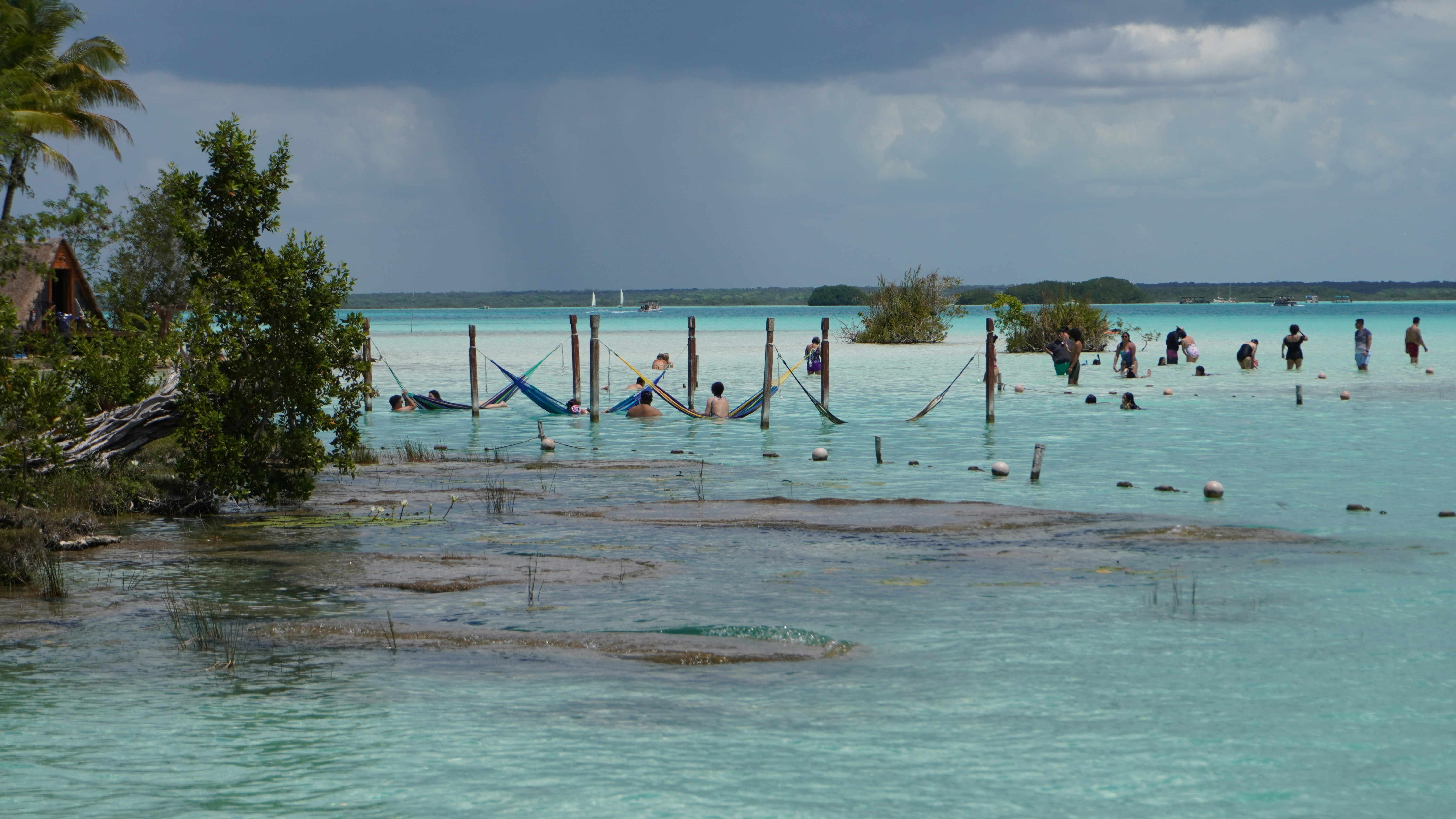 “Hammocks stretched over the crystal-clear turquoise waters of Bacalar Lagoon, creating a peaceful and relaxing tropical escape in Mexico’s Lagoon of Seven Colours.”