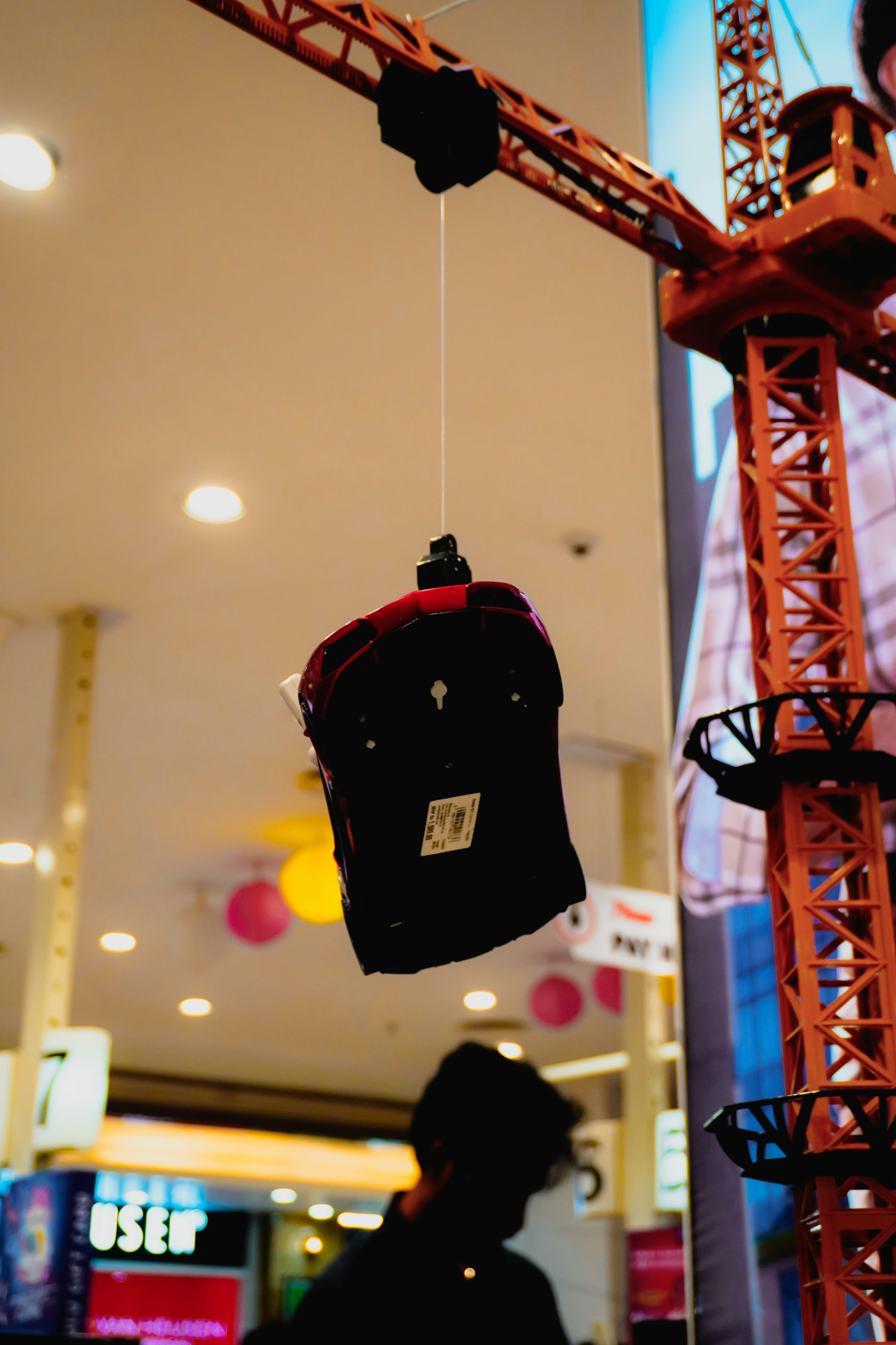 Um boné vermelho de beisebol está pendurado em um guindaste de brinquedo.