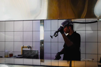 Man in black shirt and hard hat using a tool.