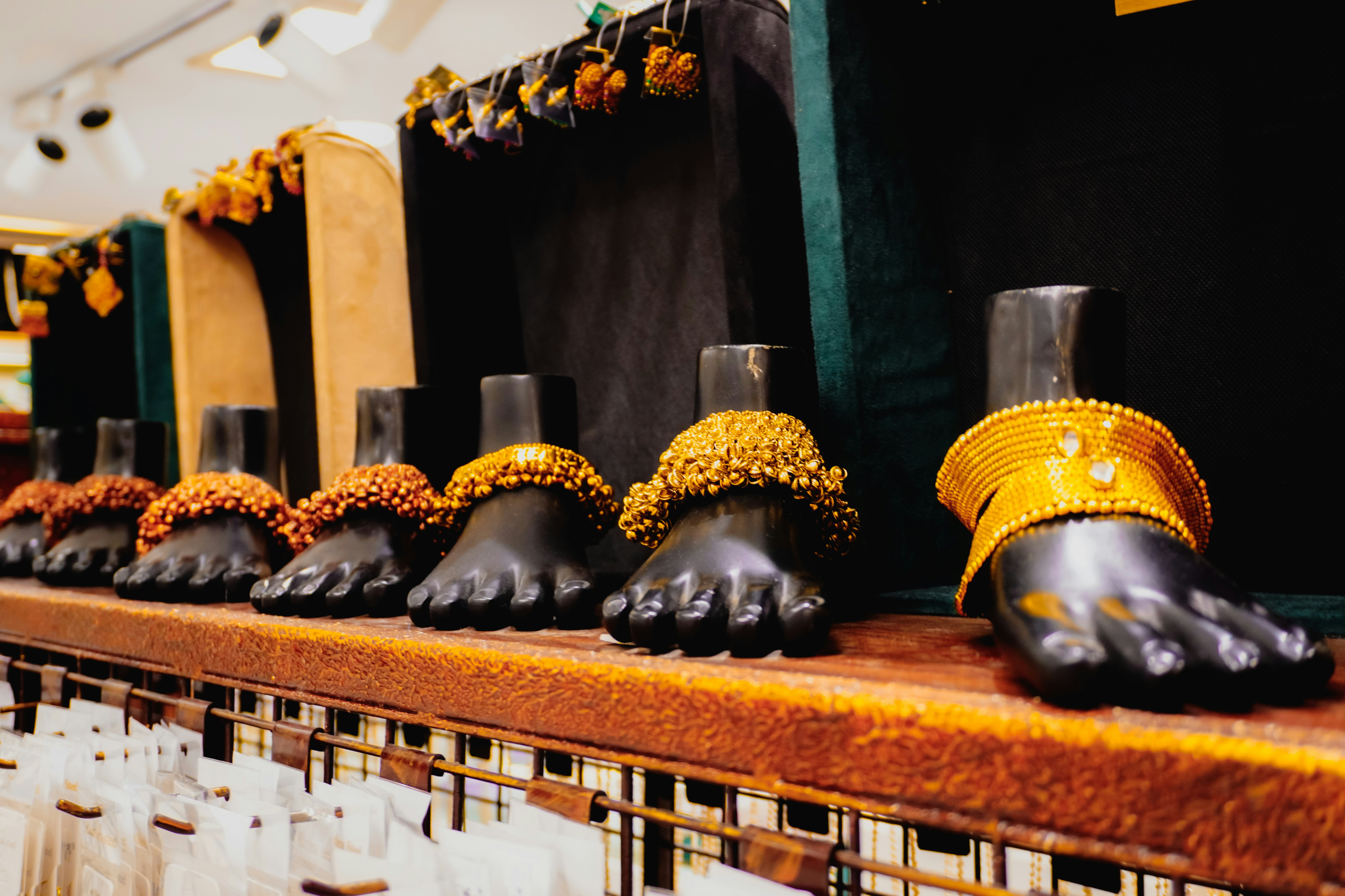 Anklets displayed on mannequin feet in a store.