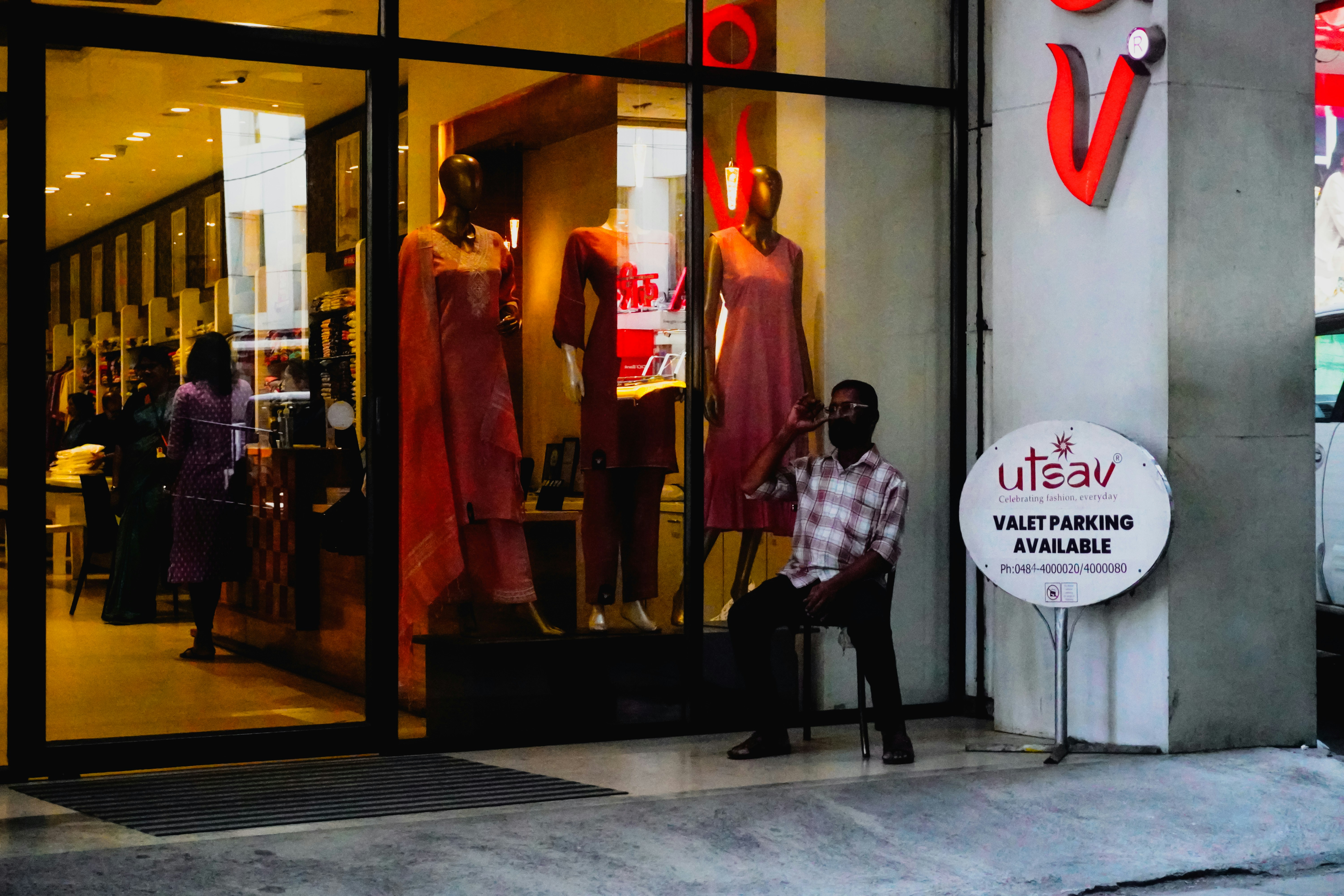 Man sitting outside a store with mannequins in window