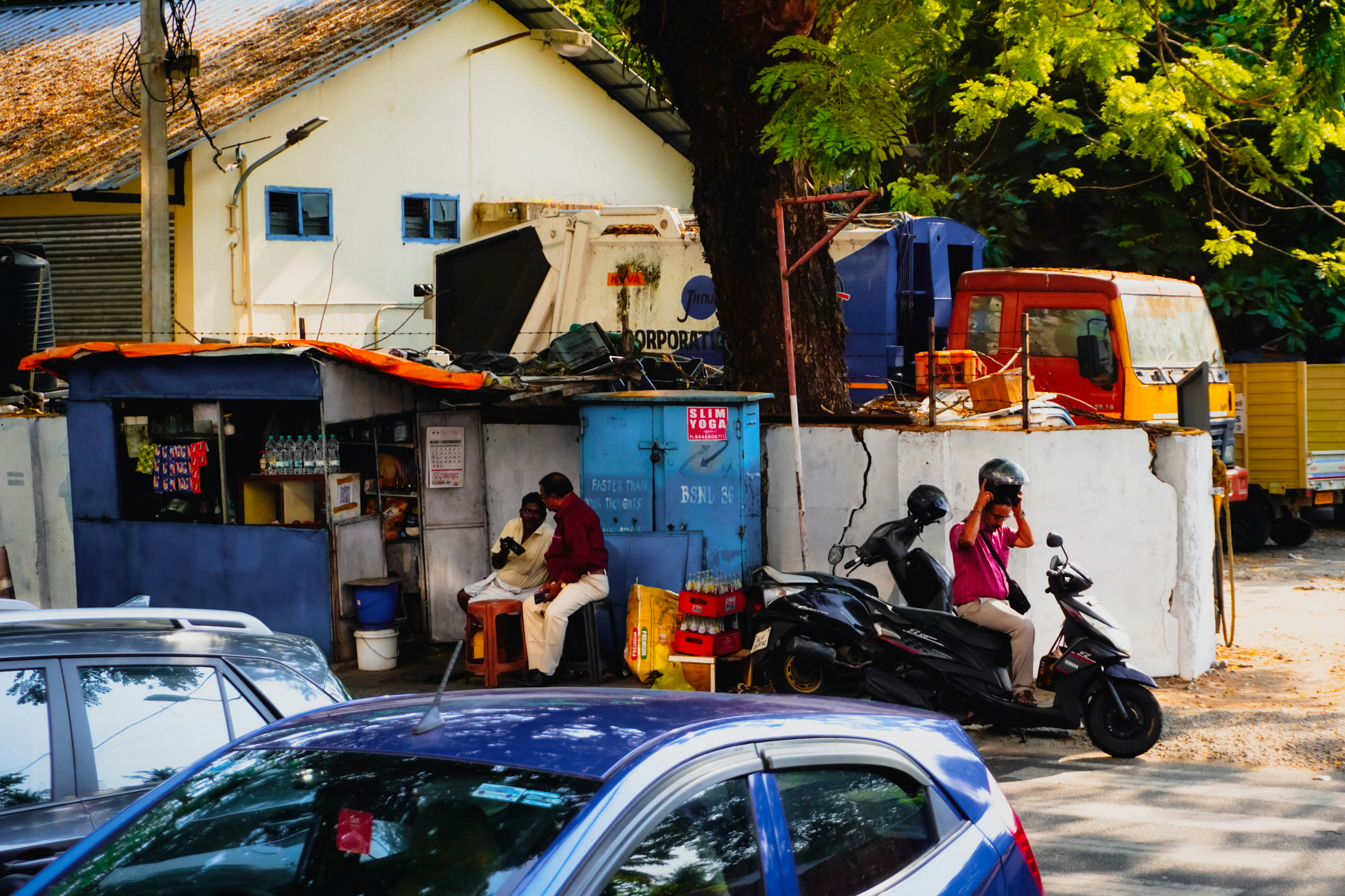 Orang dan kendaraan di dekat kios pinggir jalan.