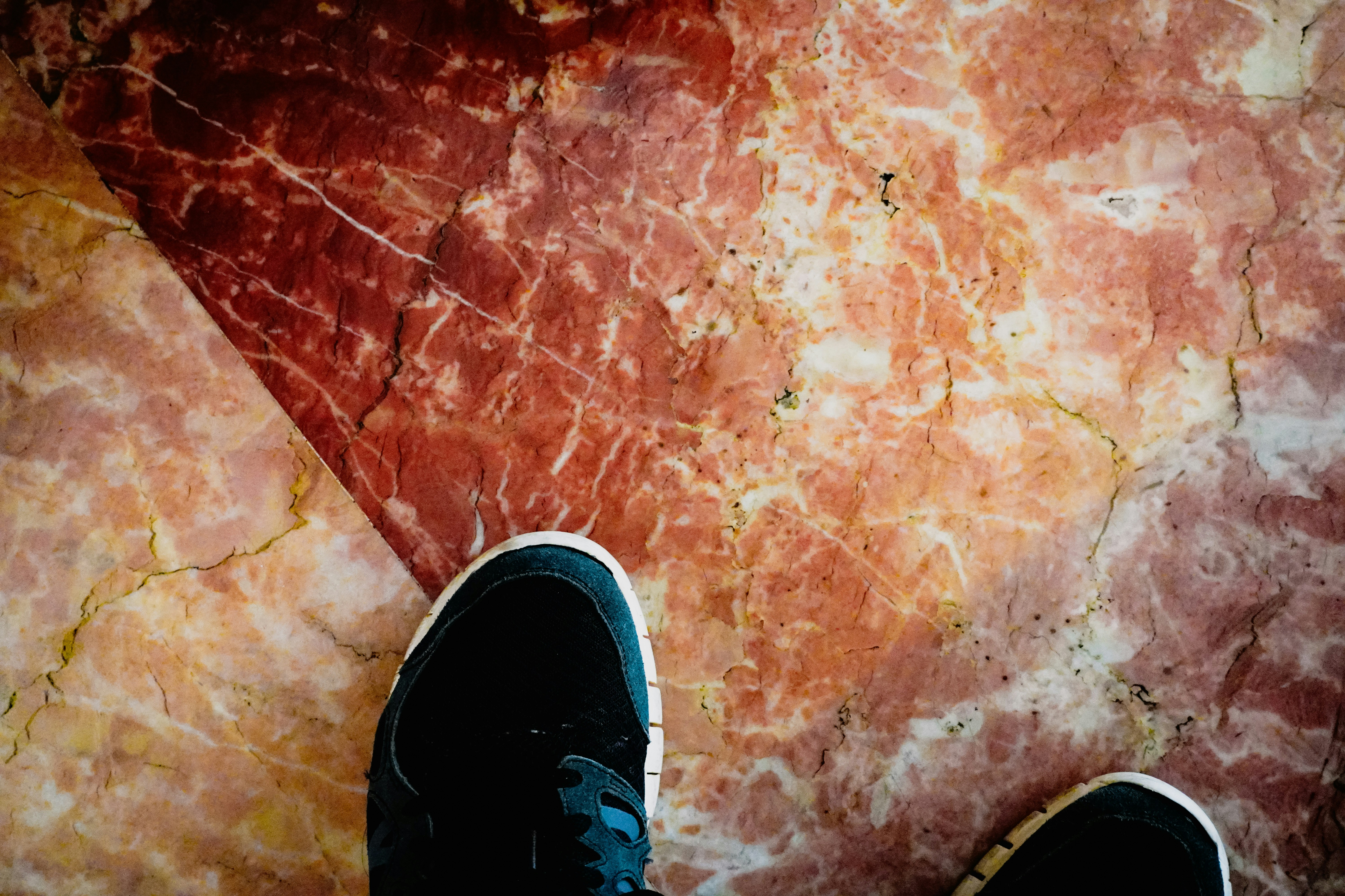 Black sneakers on a red marble floor