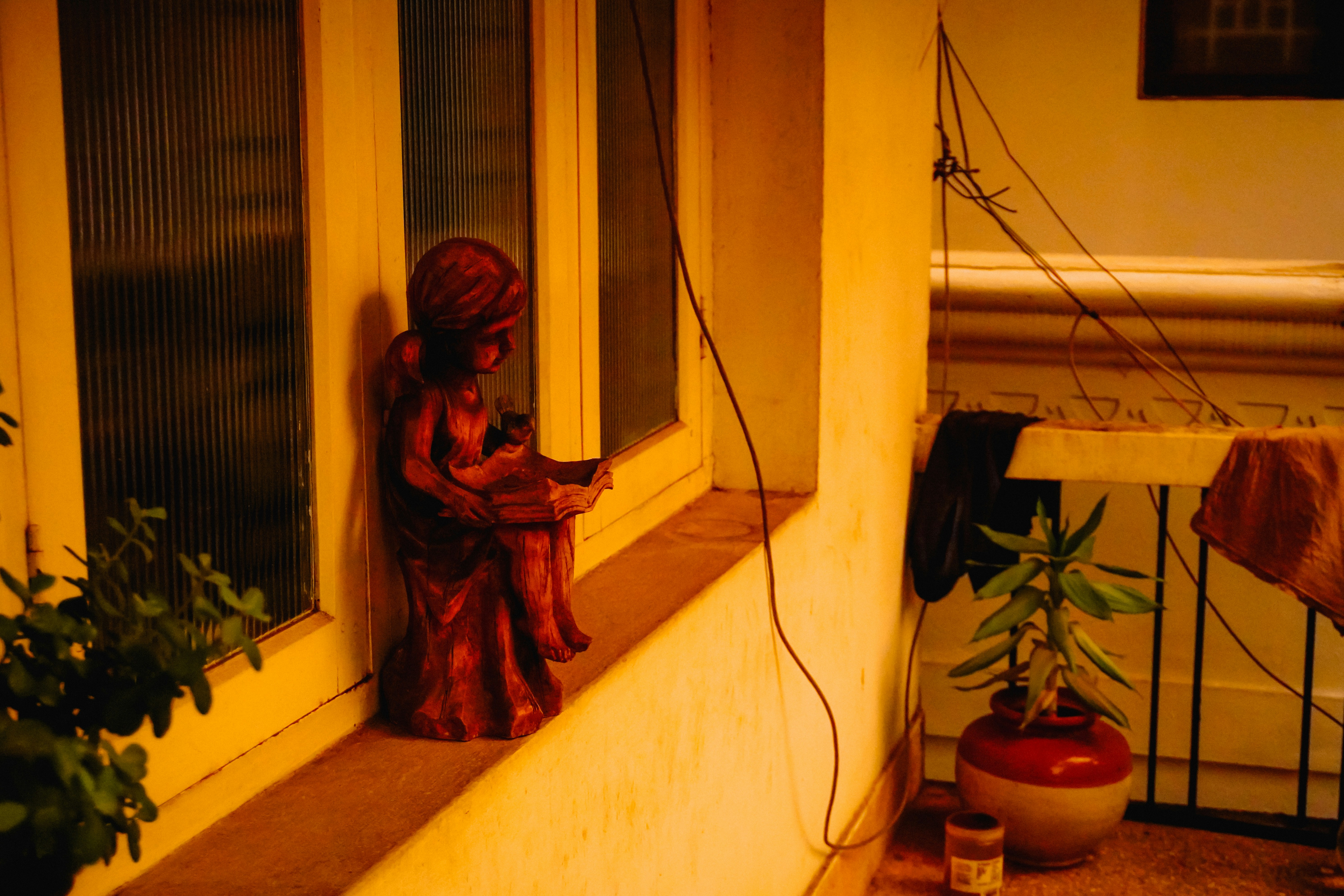 A small red angel statue sits on a windowsill.
