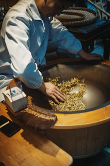 A person sorting grains in a large wooden bowl