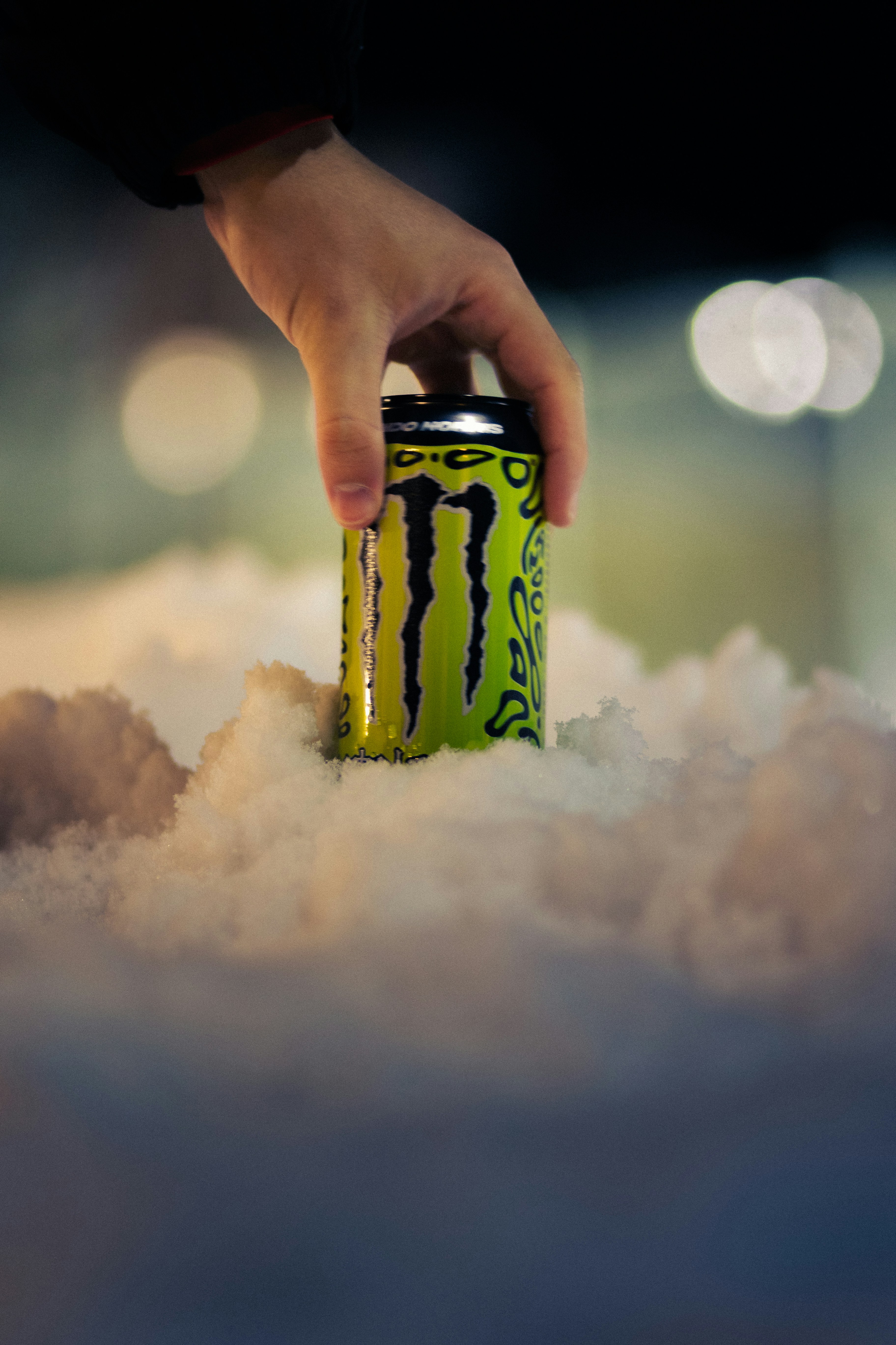 Mão estendida para pegar uma lata de bebida energética monstruosa na neve