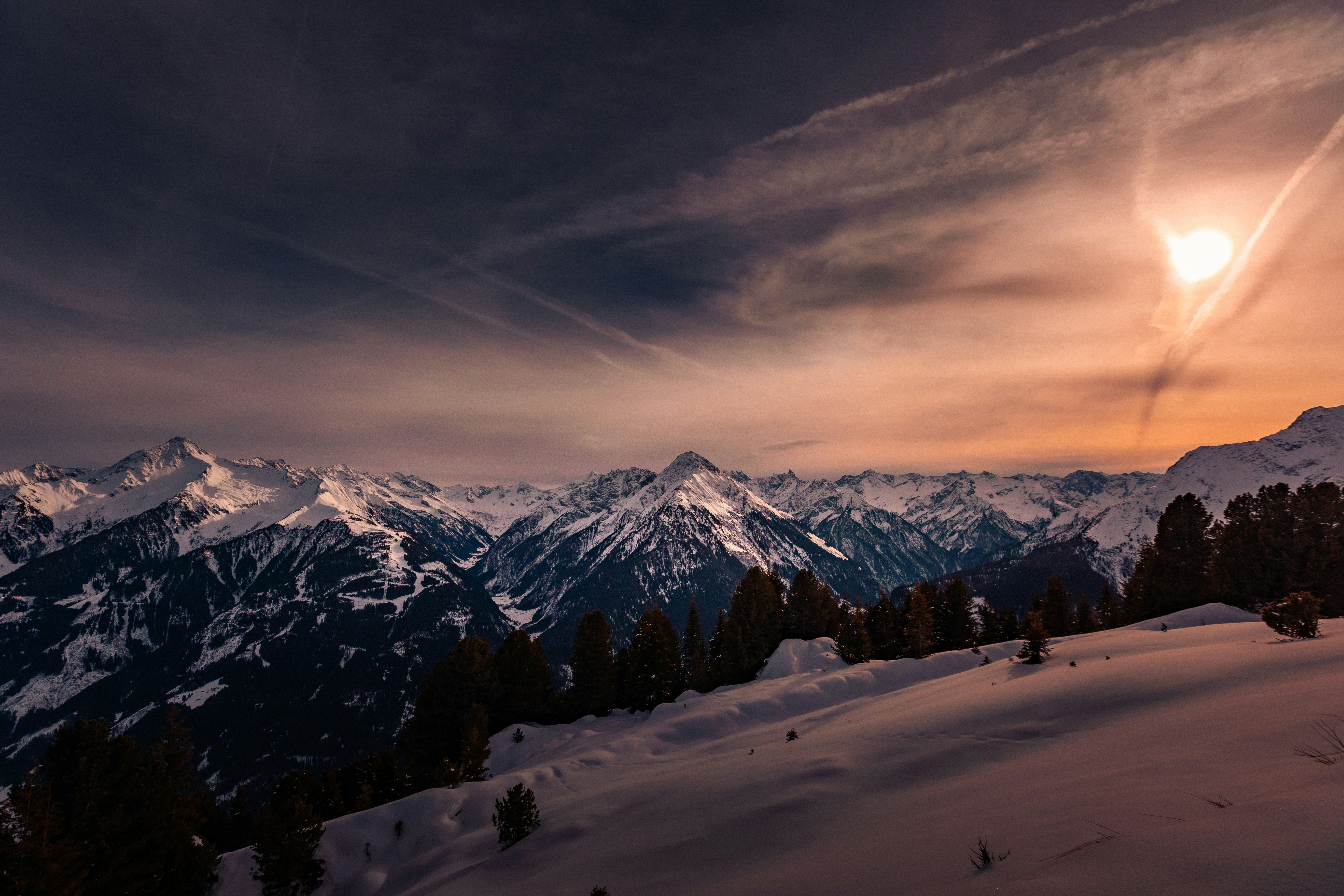 Cadeia montanhosa nevada ao pôr do sol com nuvens dramáticas