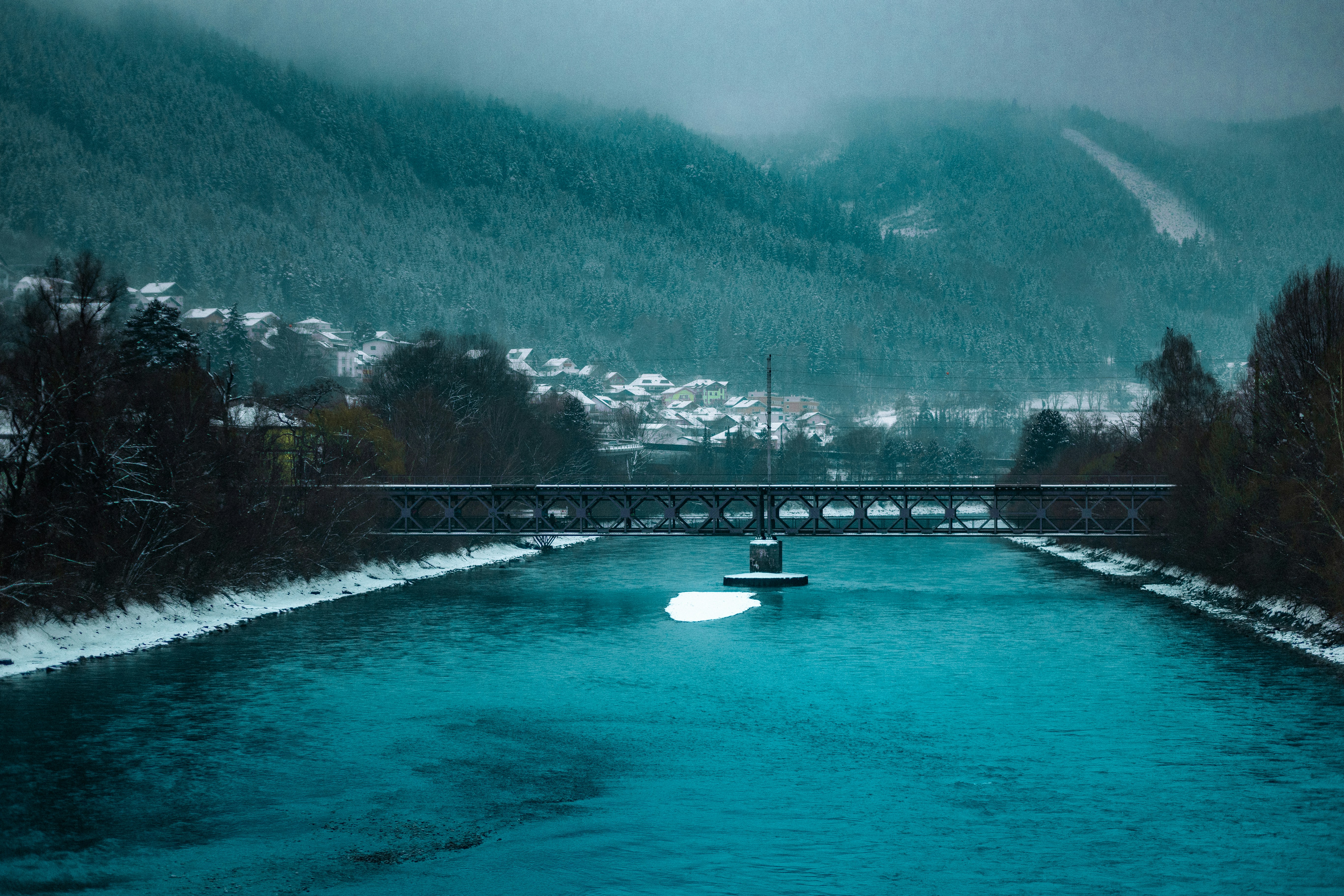 Um rio azul brilhante atravessa uma paisagem nevada.