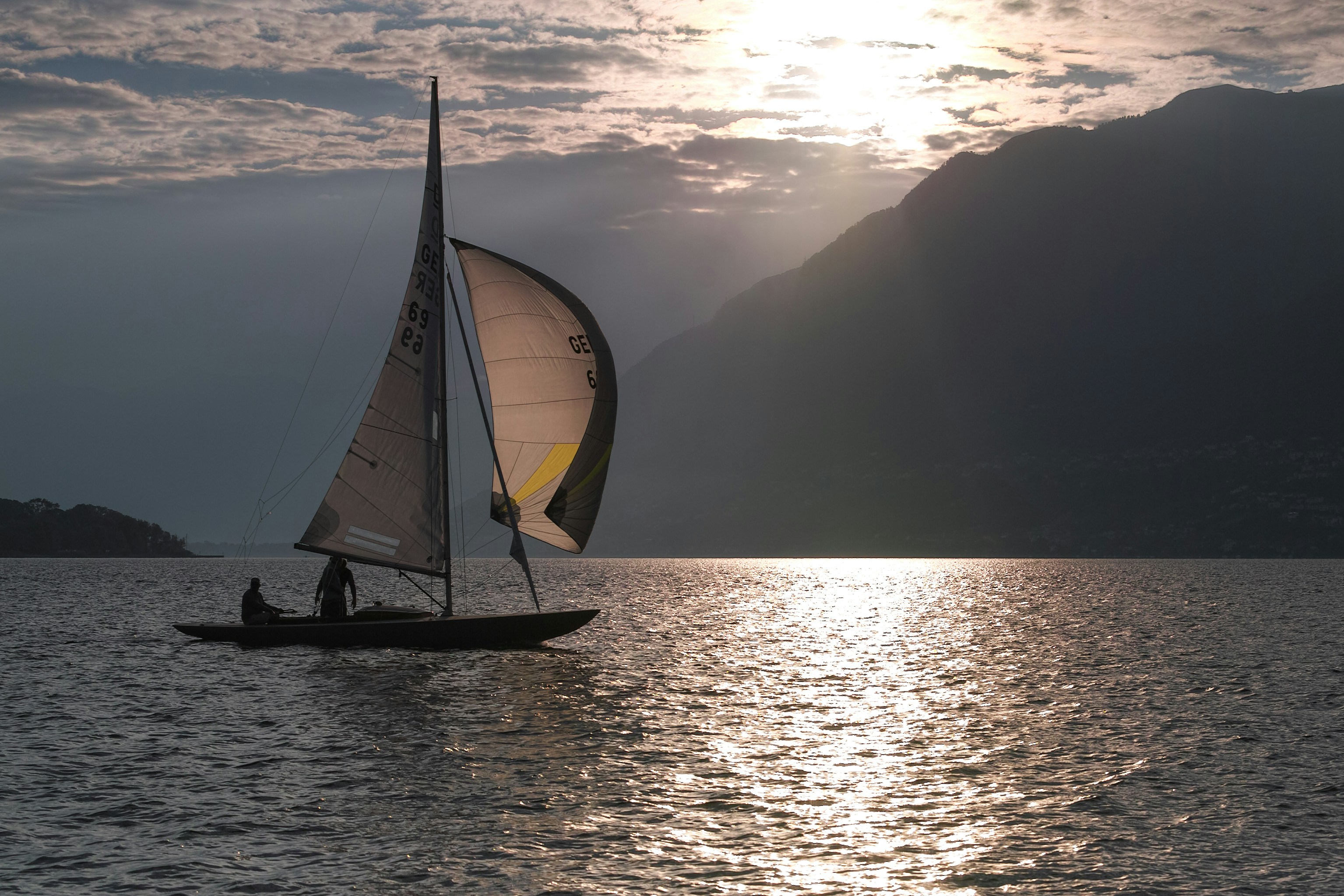 Sailboat on the water at sunset with mountains.