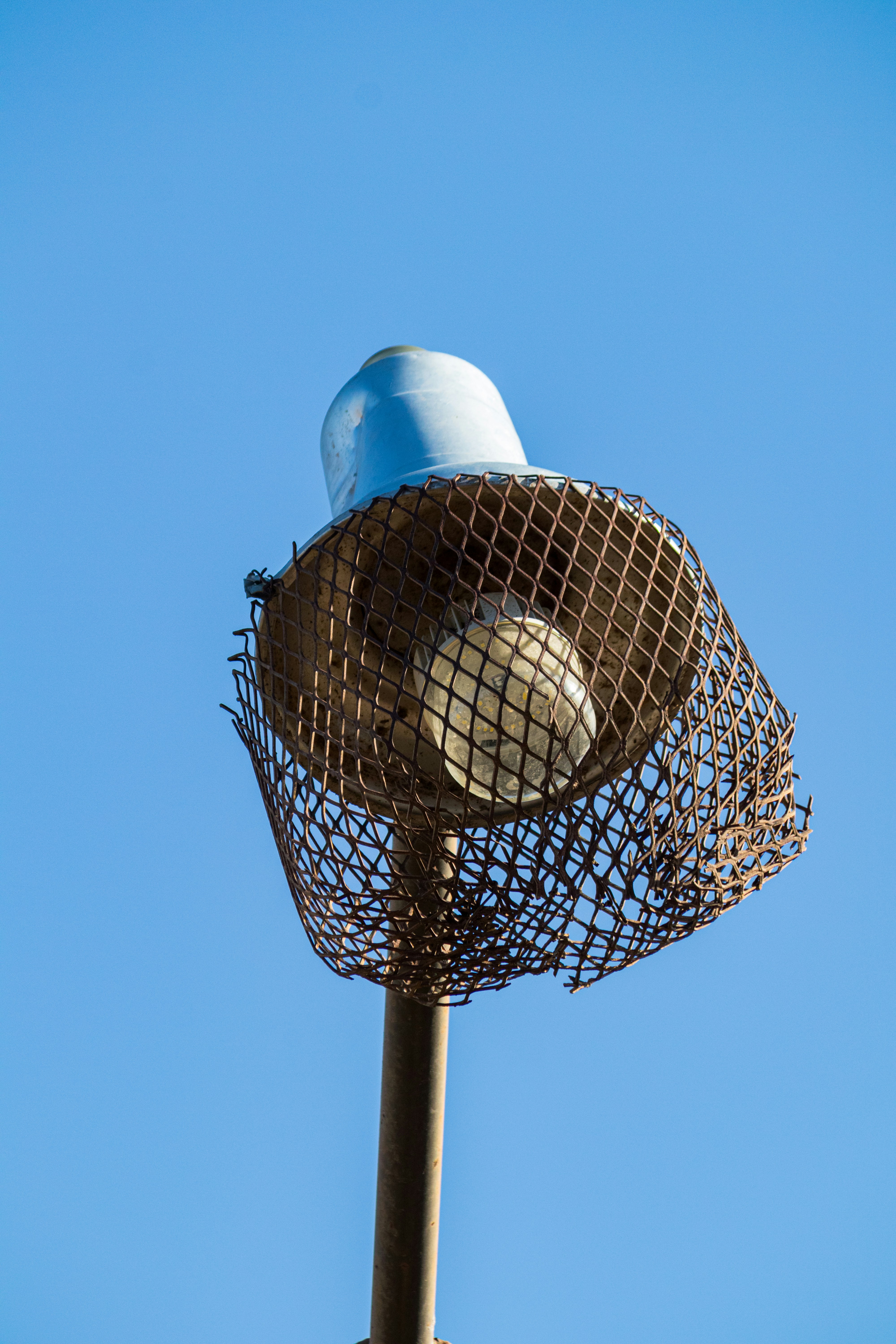 A street lamp with a lightbulb against blue sky