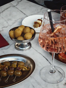 Cocktail with olives and small potatoes on marble table