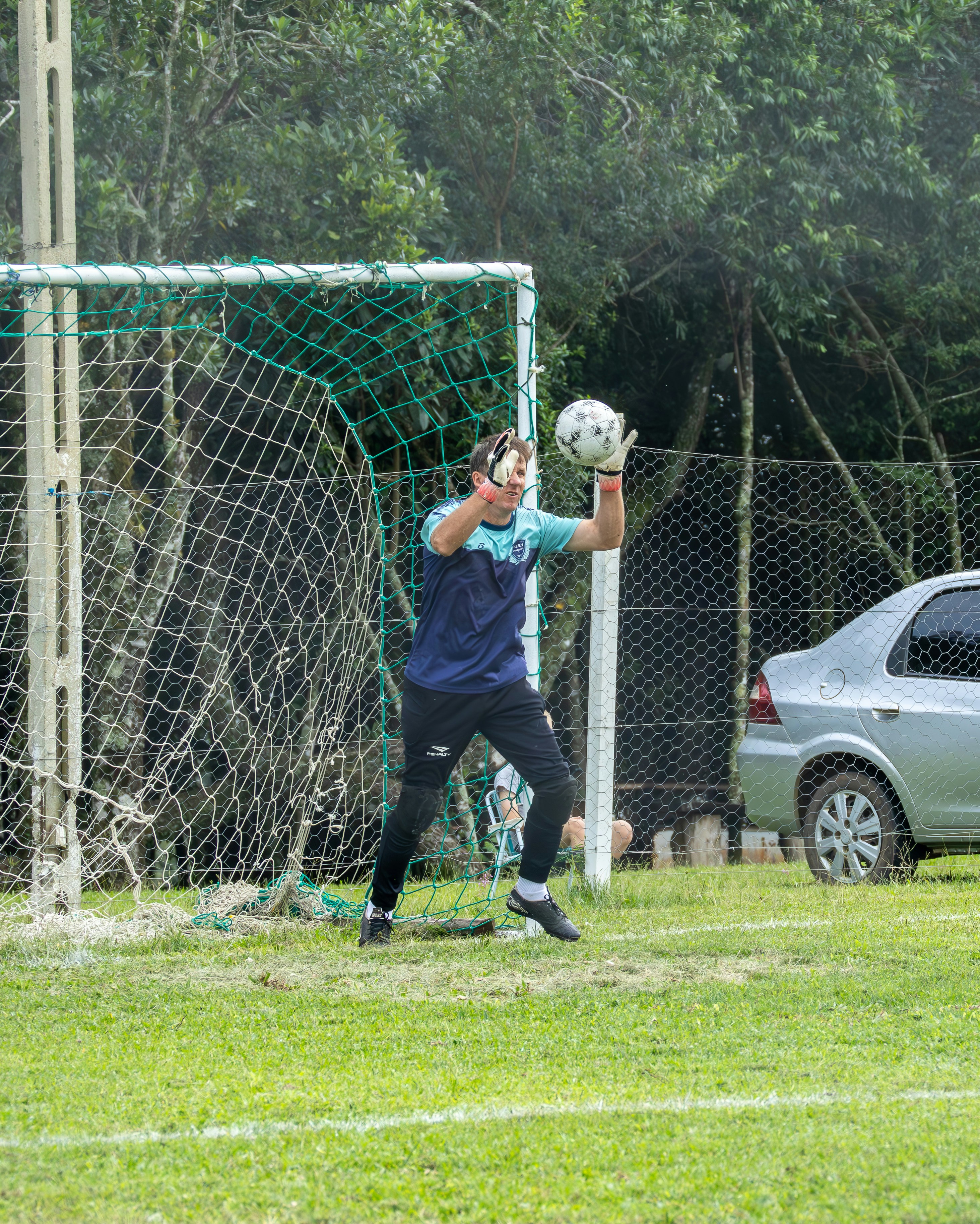 Goalkeeper catching a soccer ball near the goal.