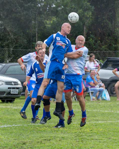Men playing soccer, jumping for the ball.