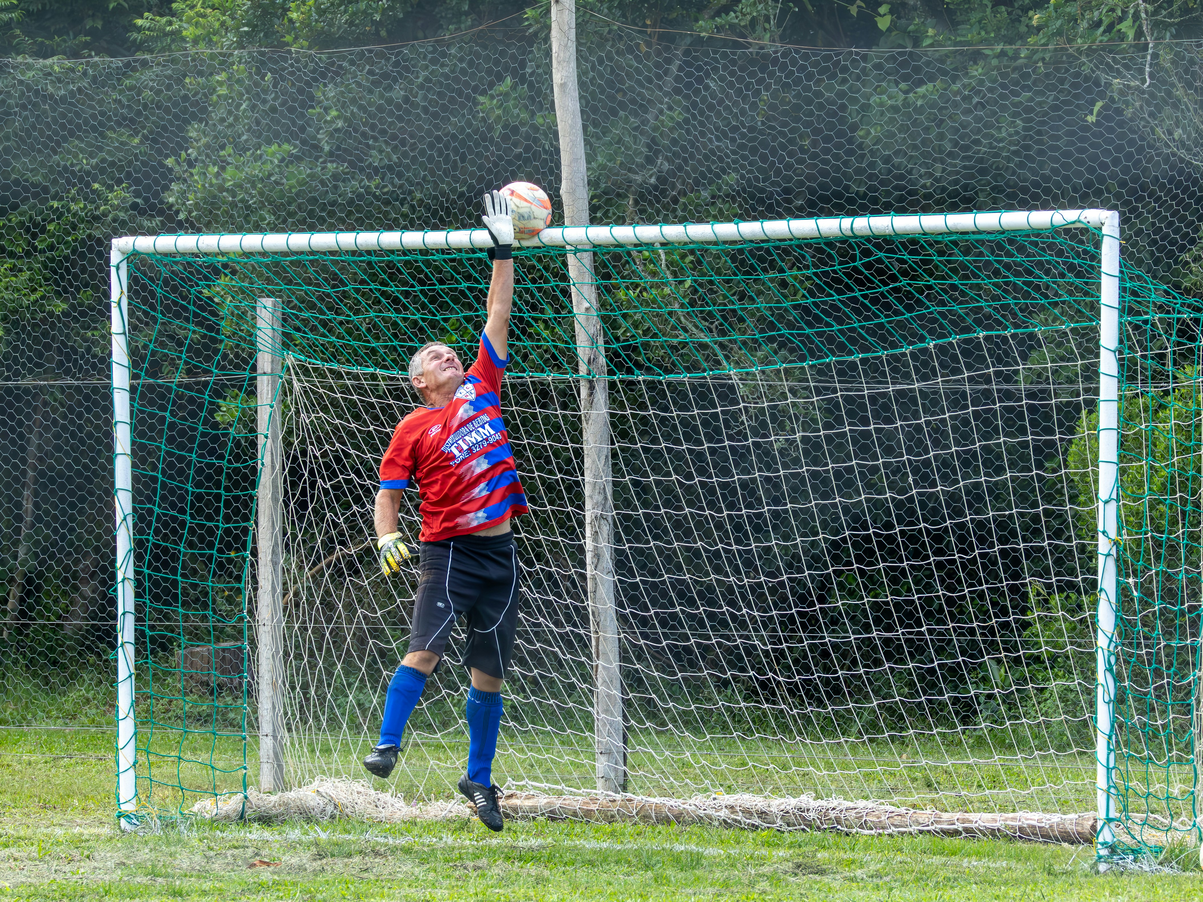 Goalkeeper jumping to catch soccer ball in net