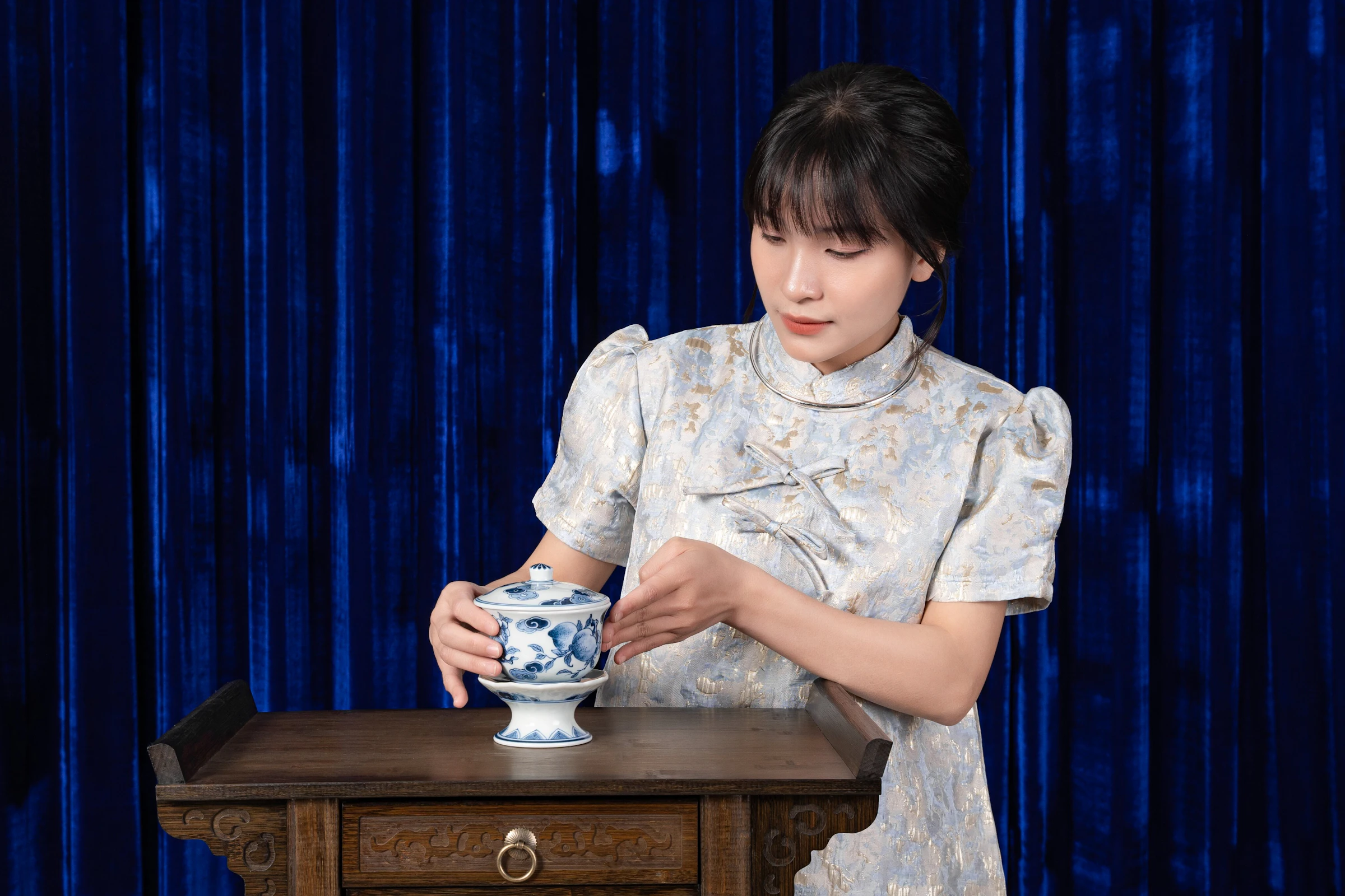 Woman closely examining a hand-painted blue-and-white porcelain vessel