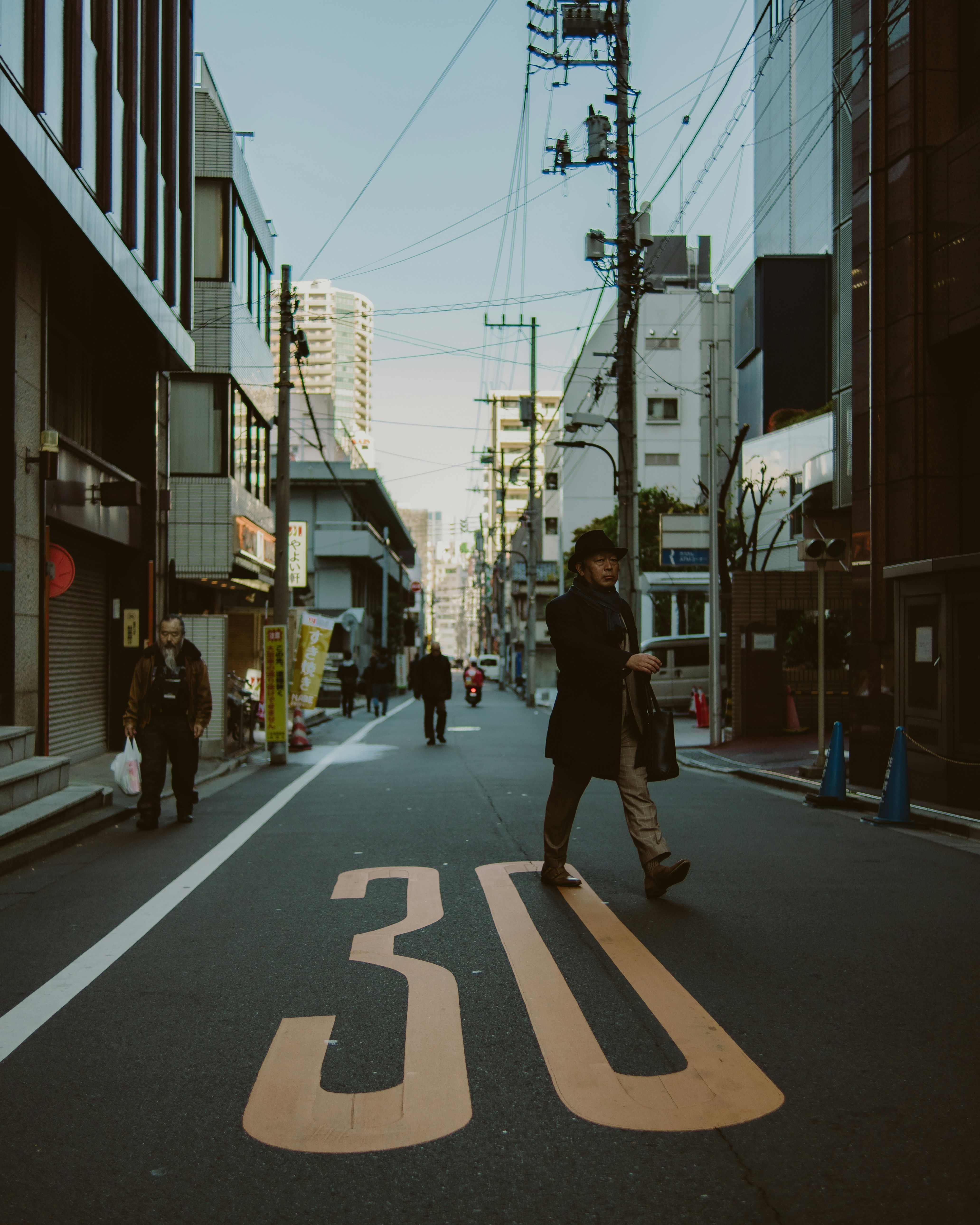 Man crosses street marked with speed limit 30.