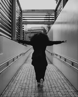 A person with curly hair walks down a ramp