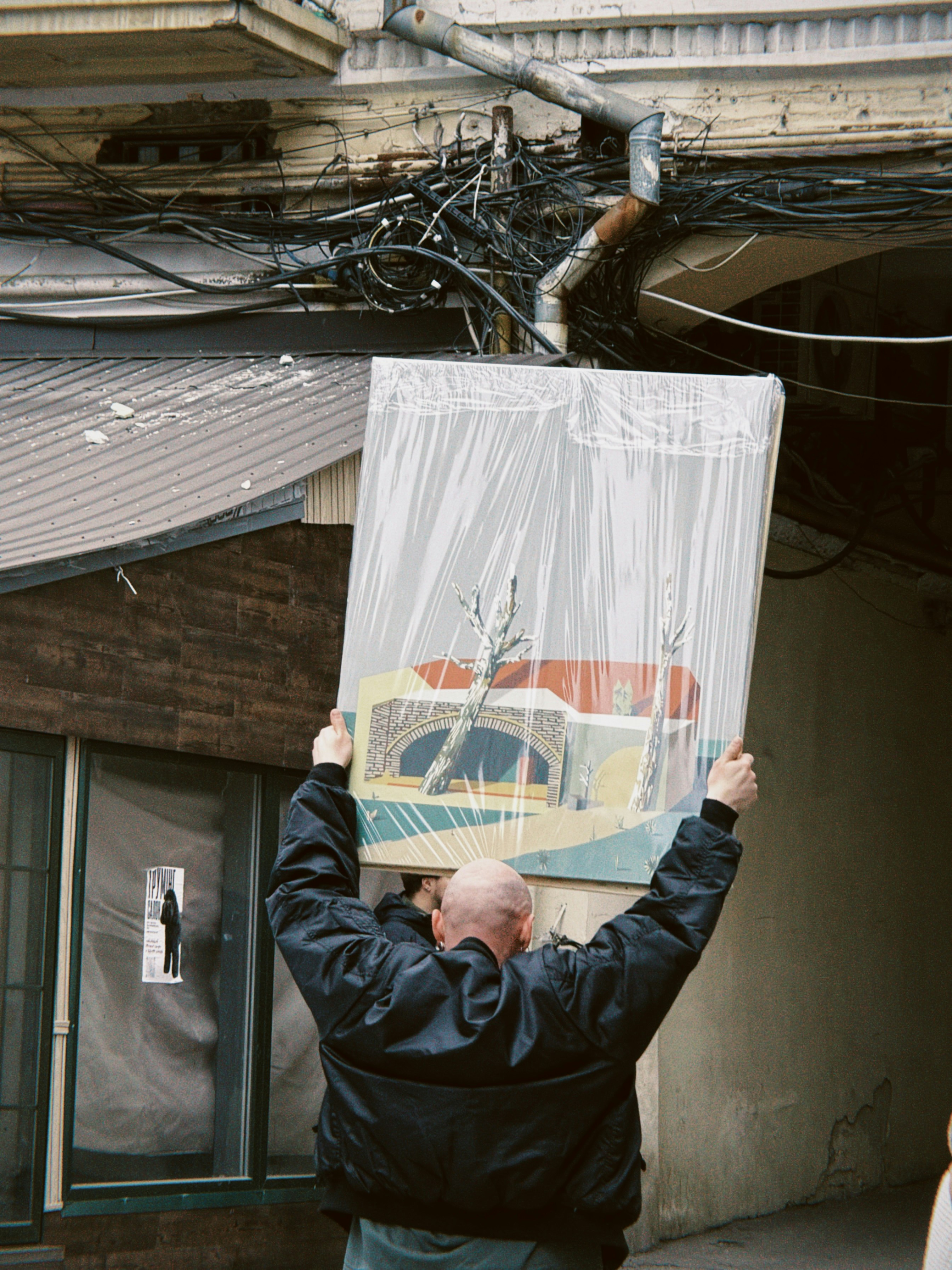 Pria membawa lukisan yang dibungkus plastik