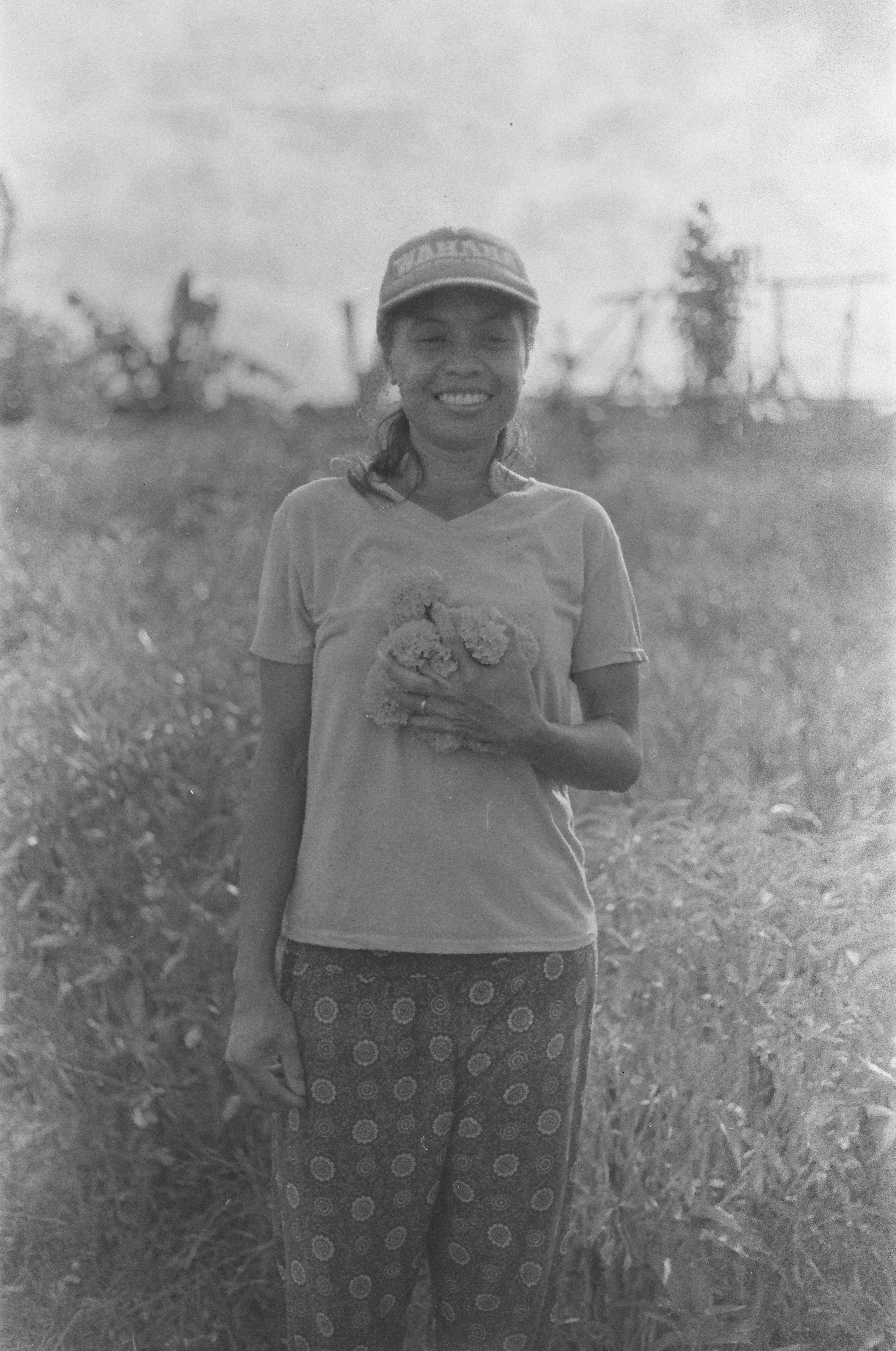 A woman holds a small object in a grassy field.