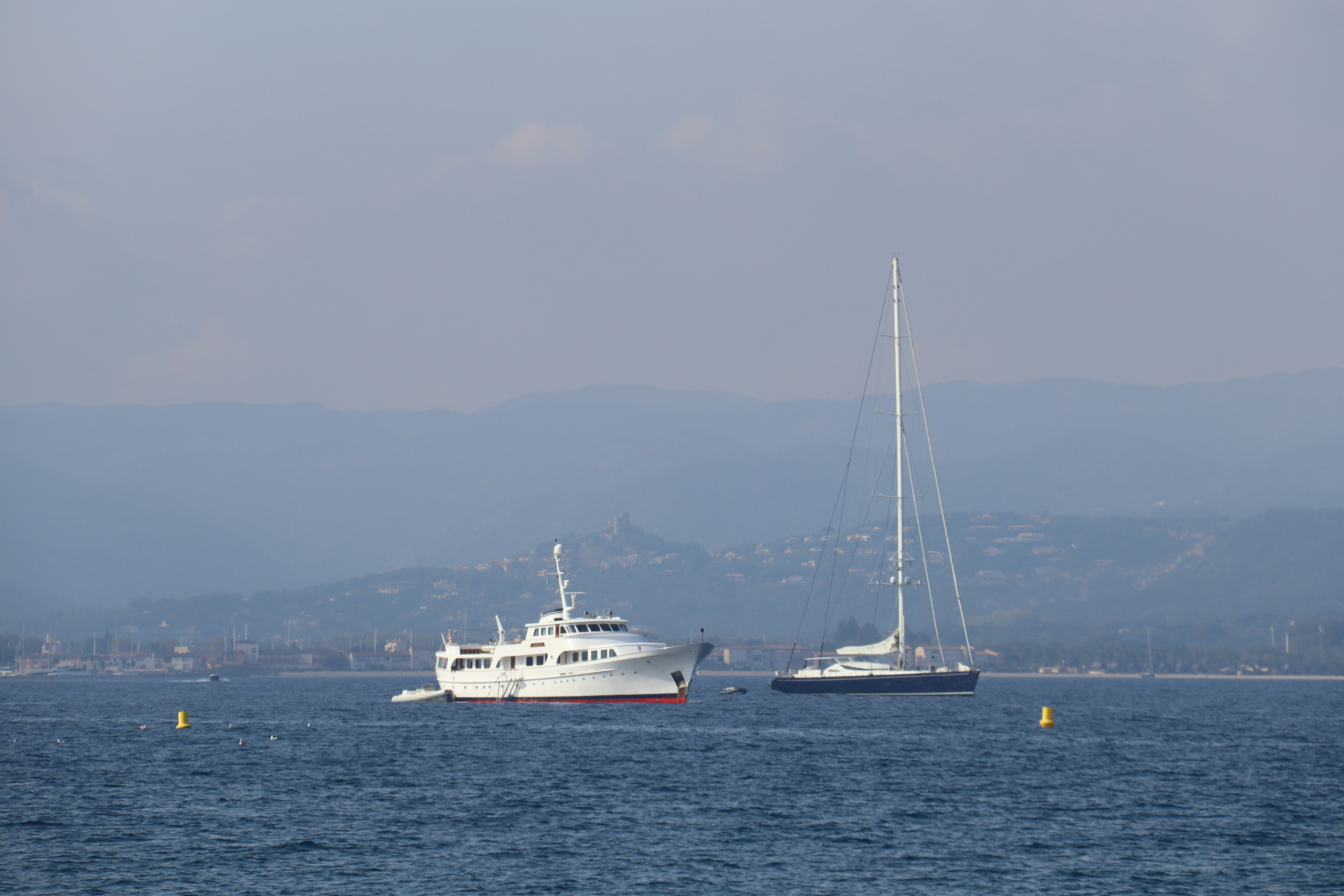 Two boats floating on the water with mountains in background