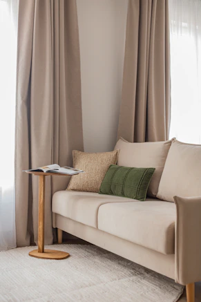 A beige sofa with decorative pillows and a side table