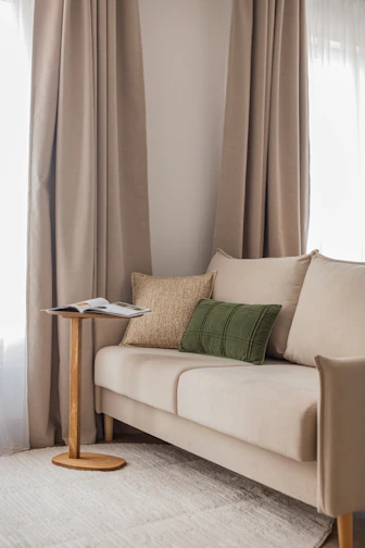 A beige sofa with decorative pillows and a side table