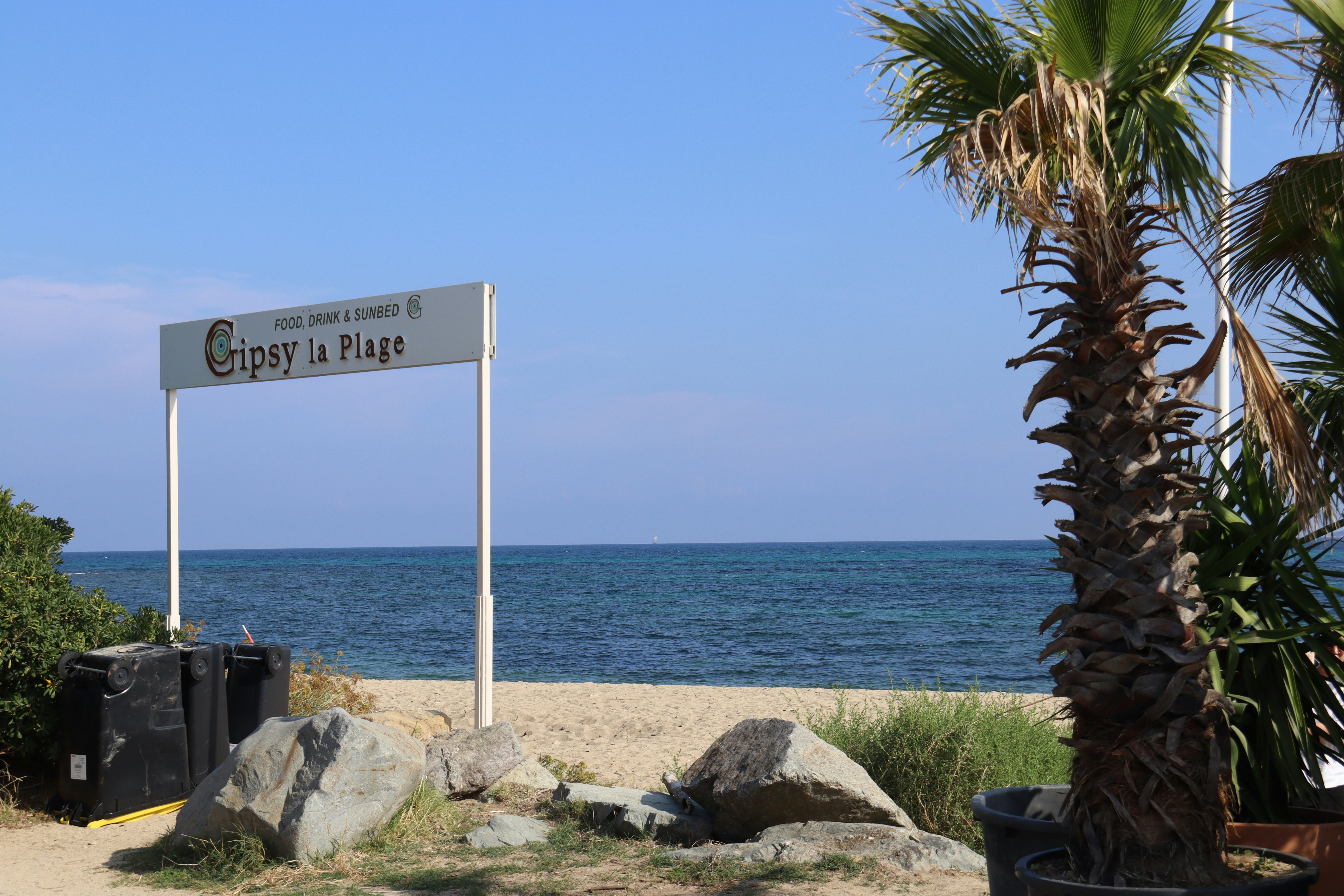Entrada a la playa con palmera y cartel