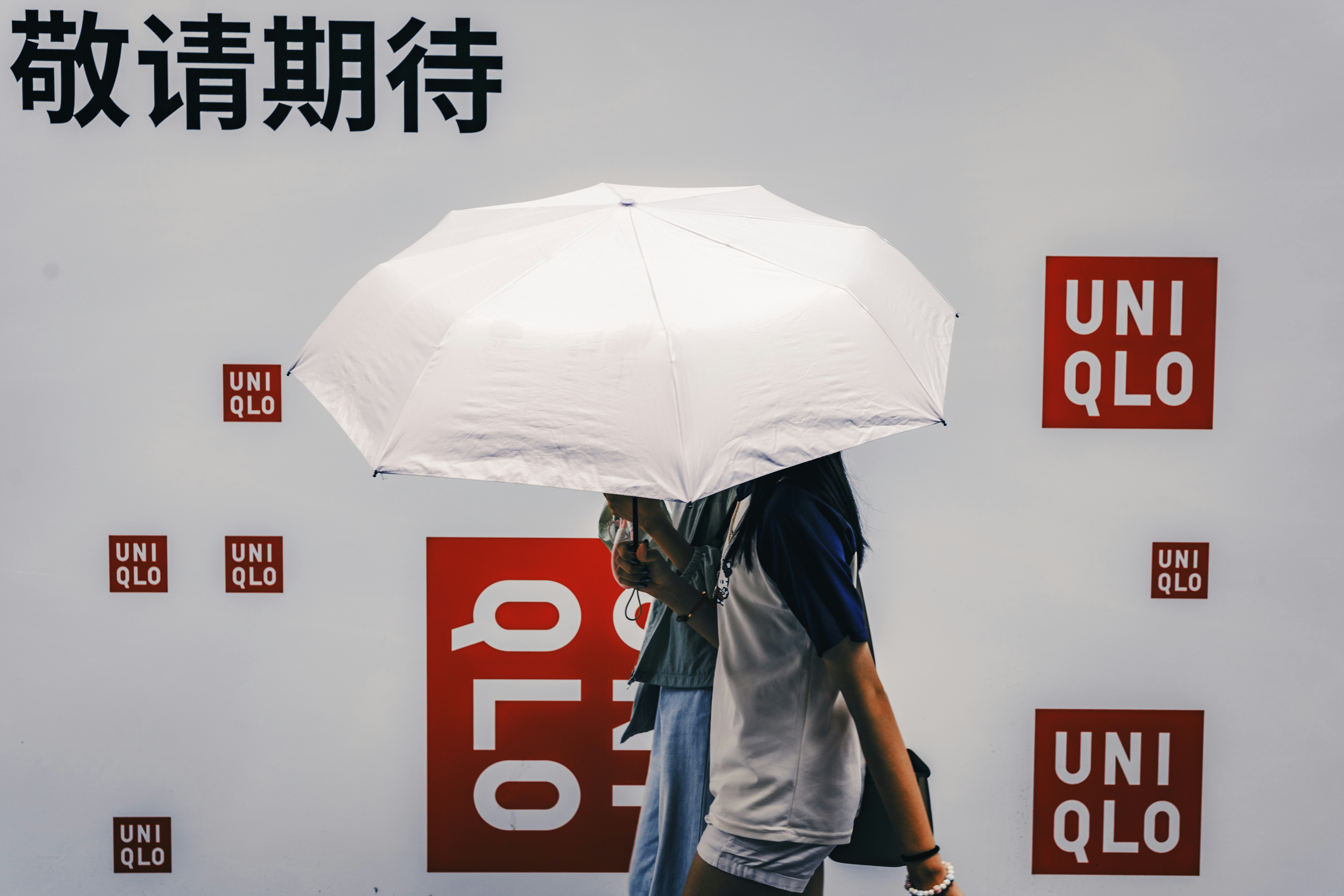 Les gens passent sous un parapluie avec les logos Uniqlo.