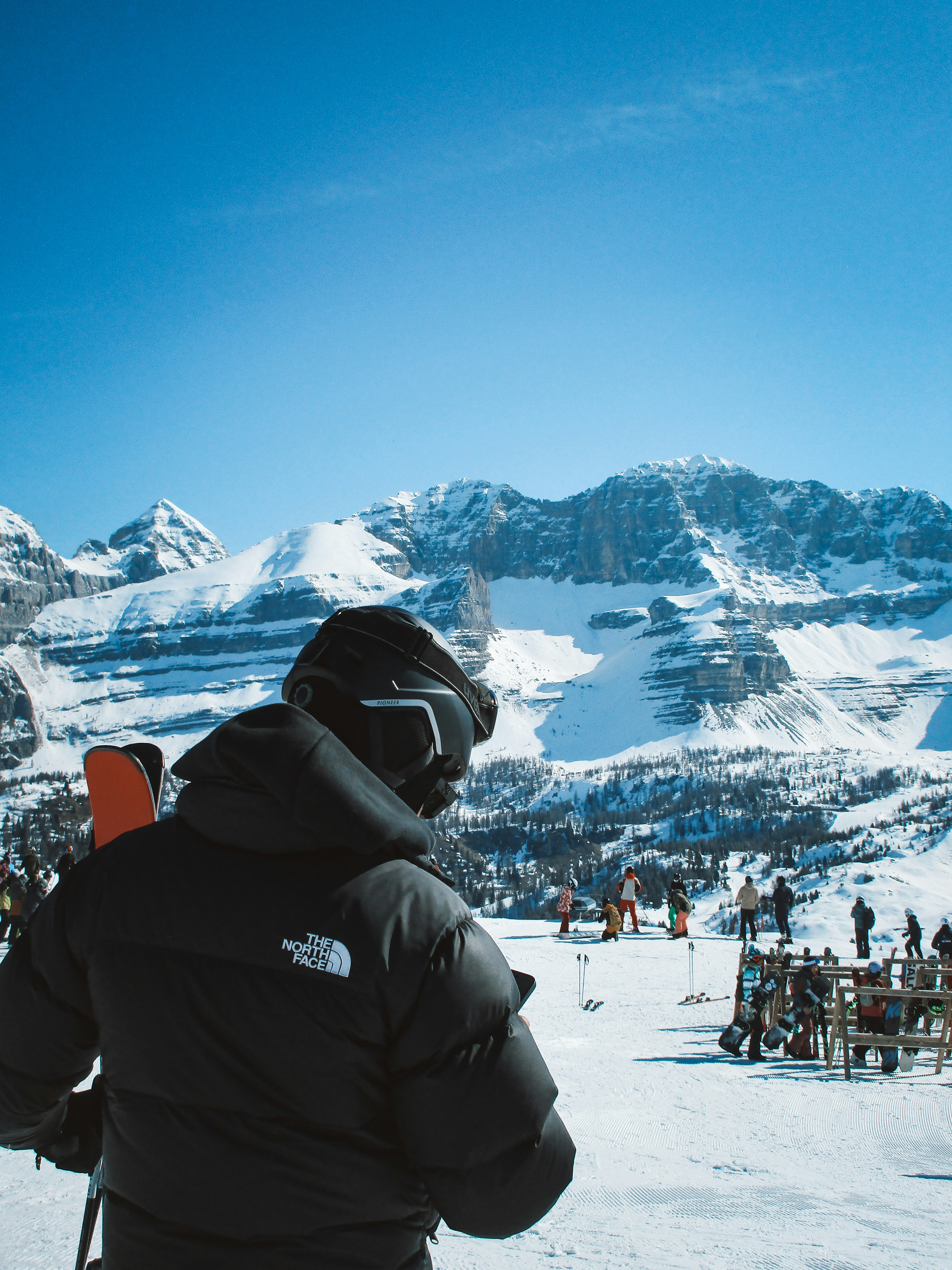 Skier looking at snowy mountains under a clear blue sky.