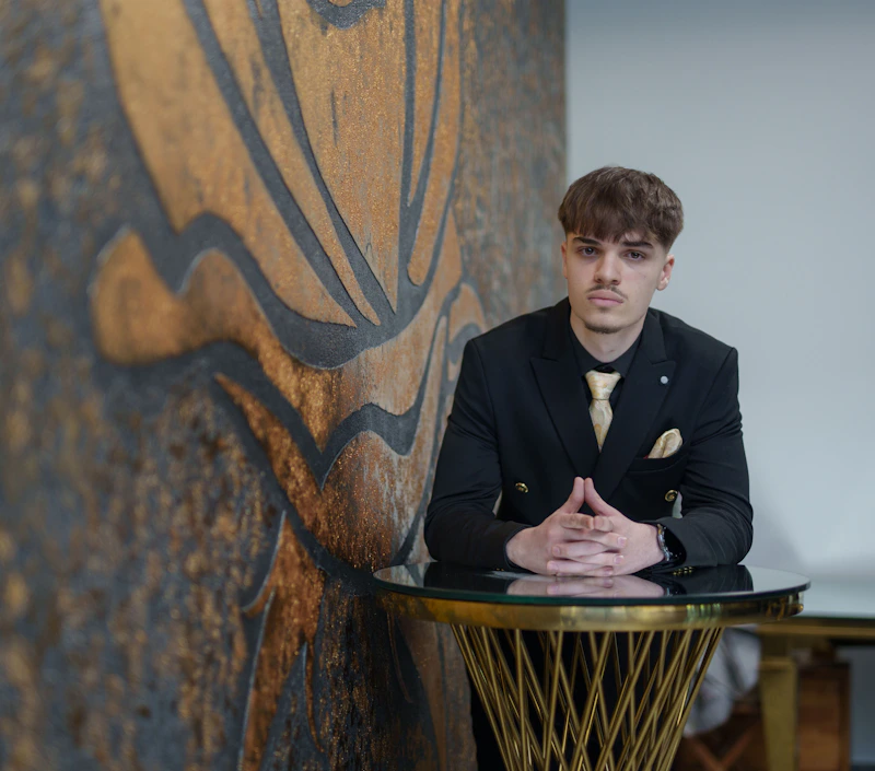 Un sugar boy español joven en traje, apoyado en una mesa