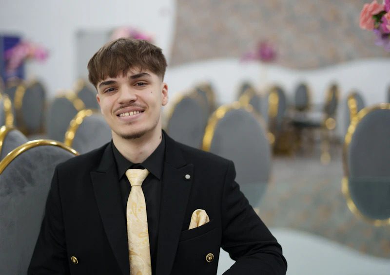 jeune sugar daddy souriant en costume noir et cravate dorée