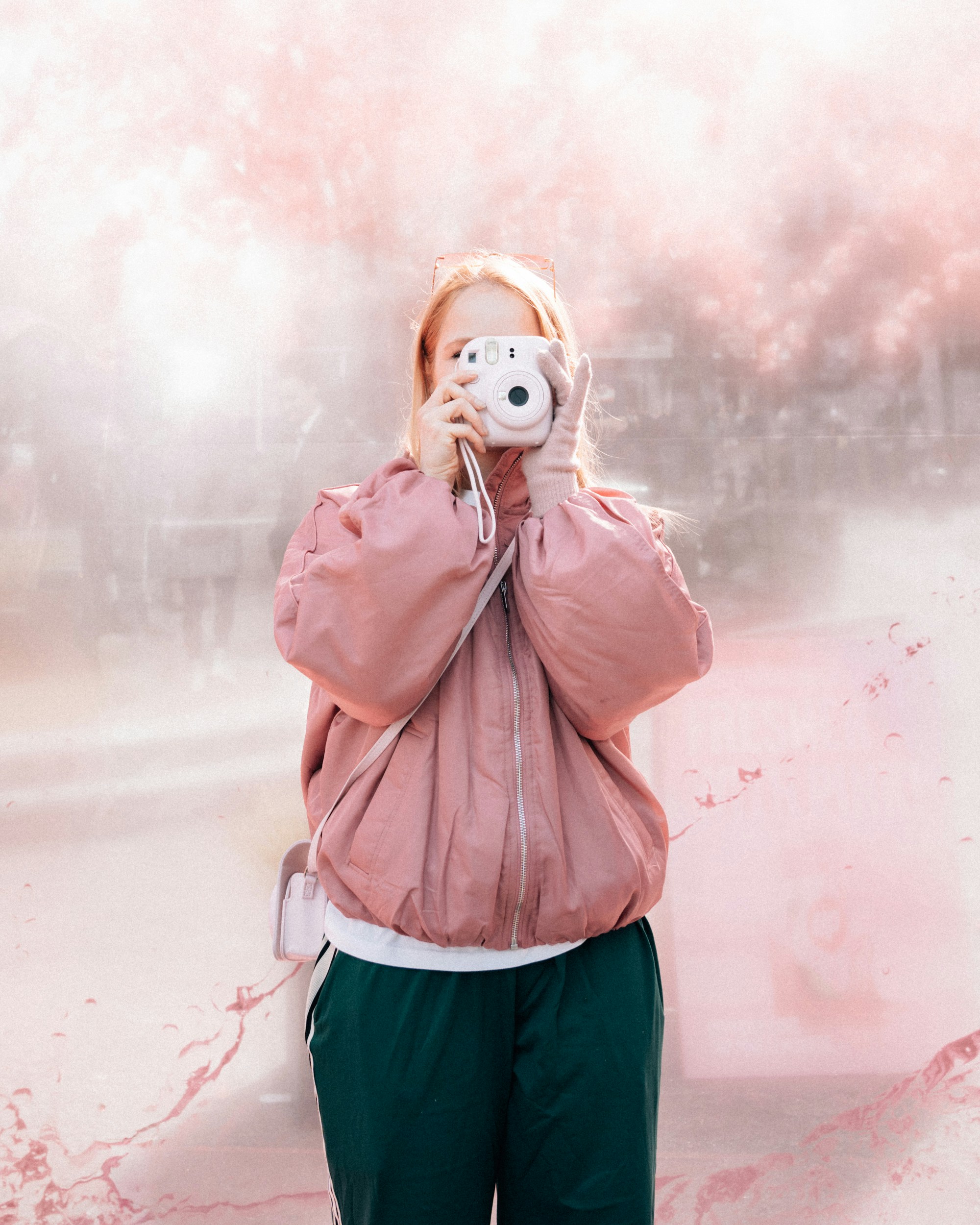 Woman in pink jacket taking a photo with instant camera