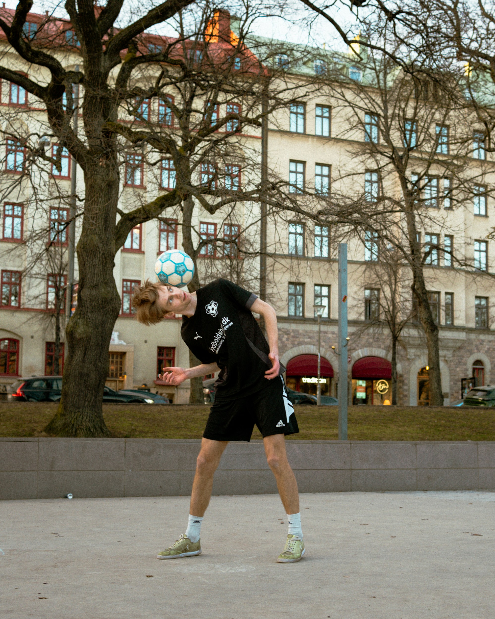 Young man balancing soccer ball on his head outdoors
