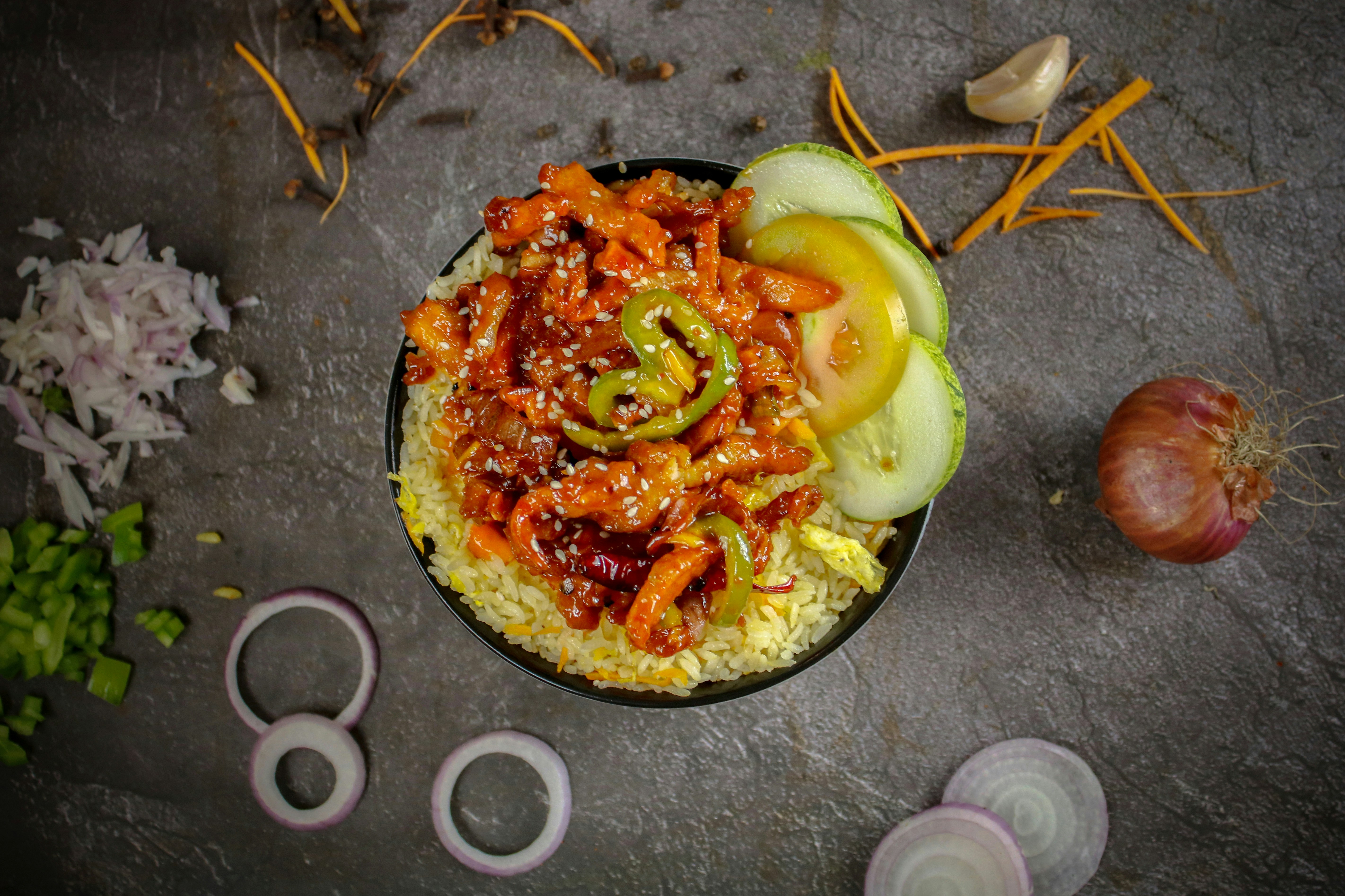 Spicy chicken and rice bowl with cucumber and onion
