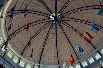 Flags of various nations hang inside a domed building.