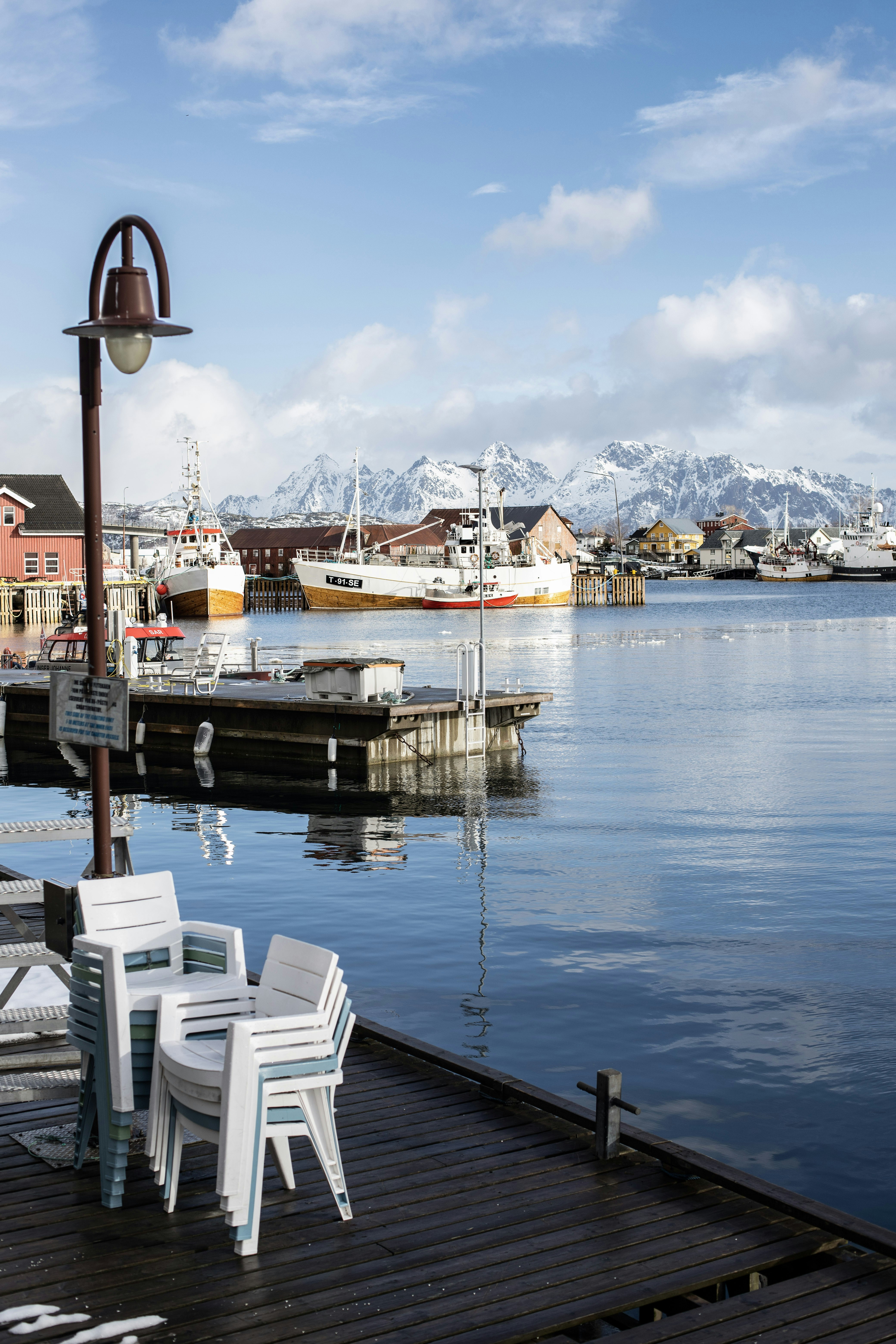 Barcos atracados en un puerto con montañas nevadas.