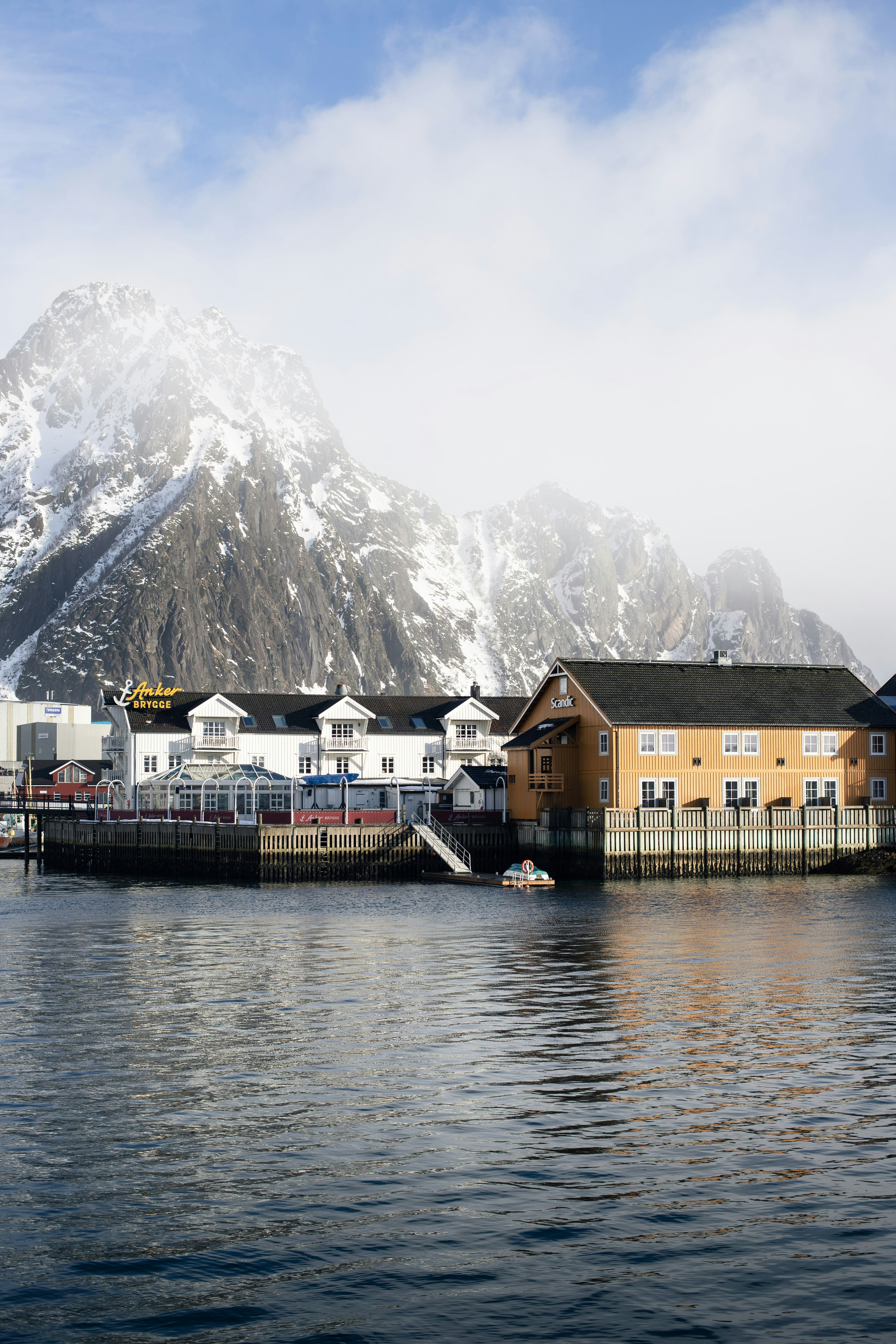 Pueblo costero con montañas nevadas al fondo.