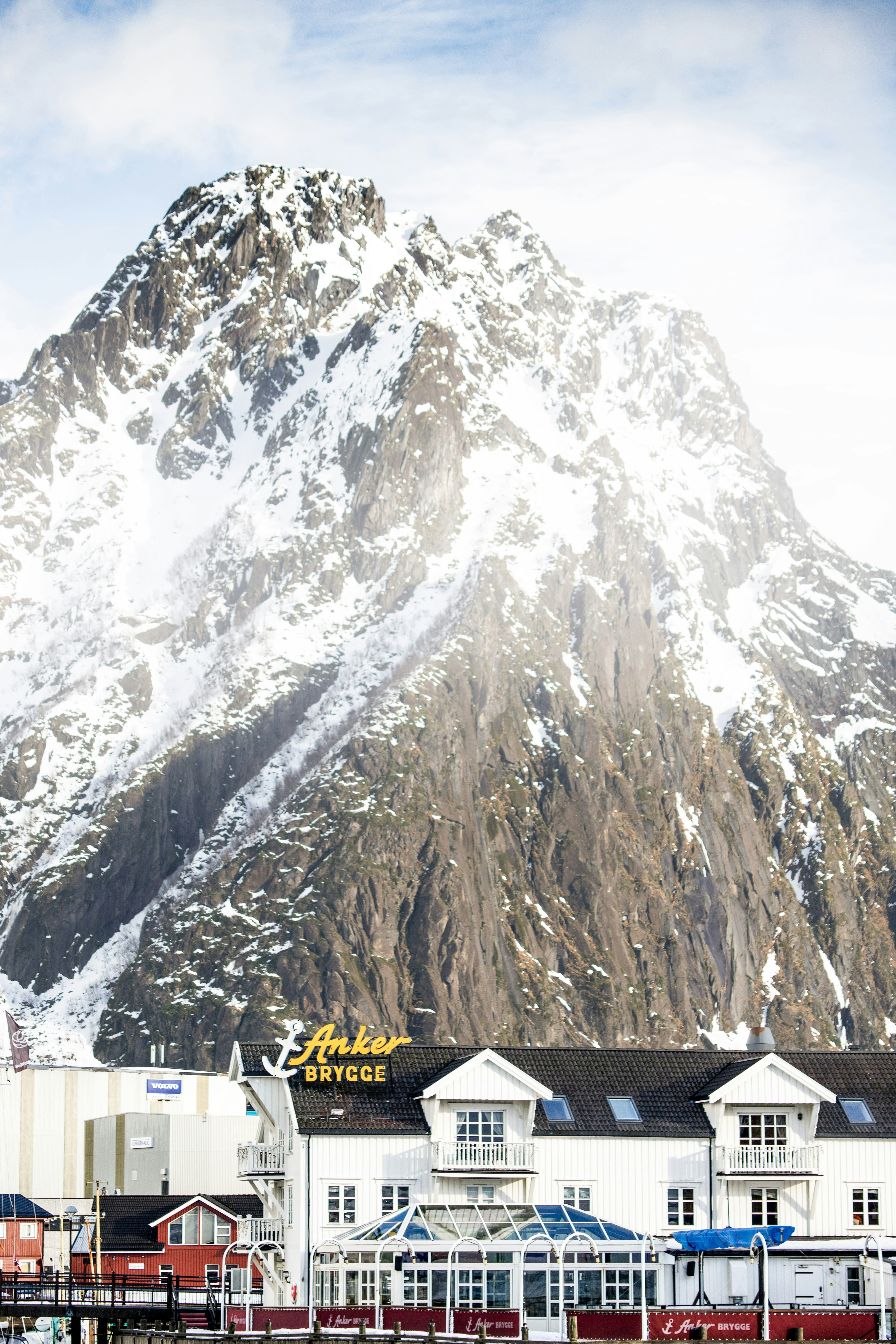 Montañas nevadas se alzan sobre edificios blancos junto al agua.