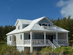 A light blue beach house with white trim and railings.