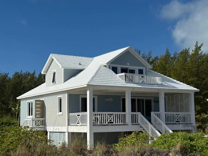 A light blue beach house with white trim and railings.