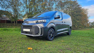 Dark grey van parked on a grassy field.