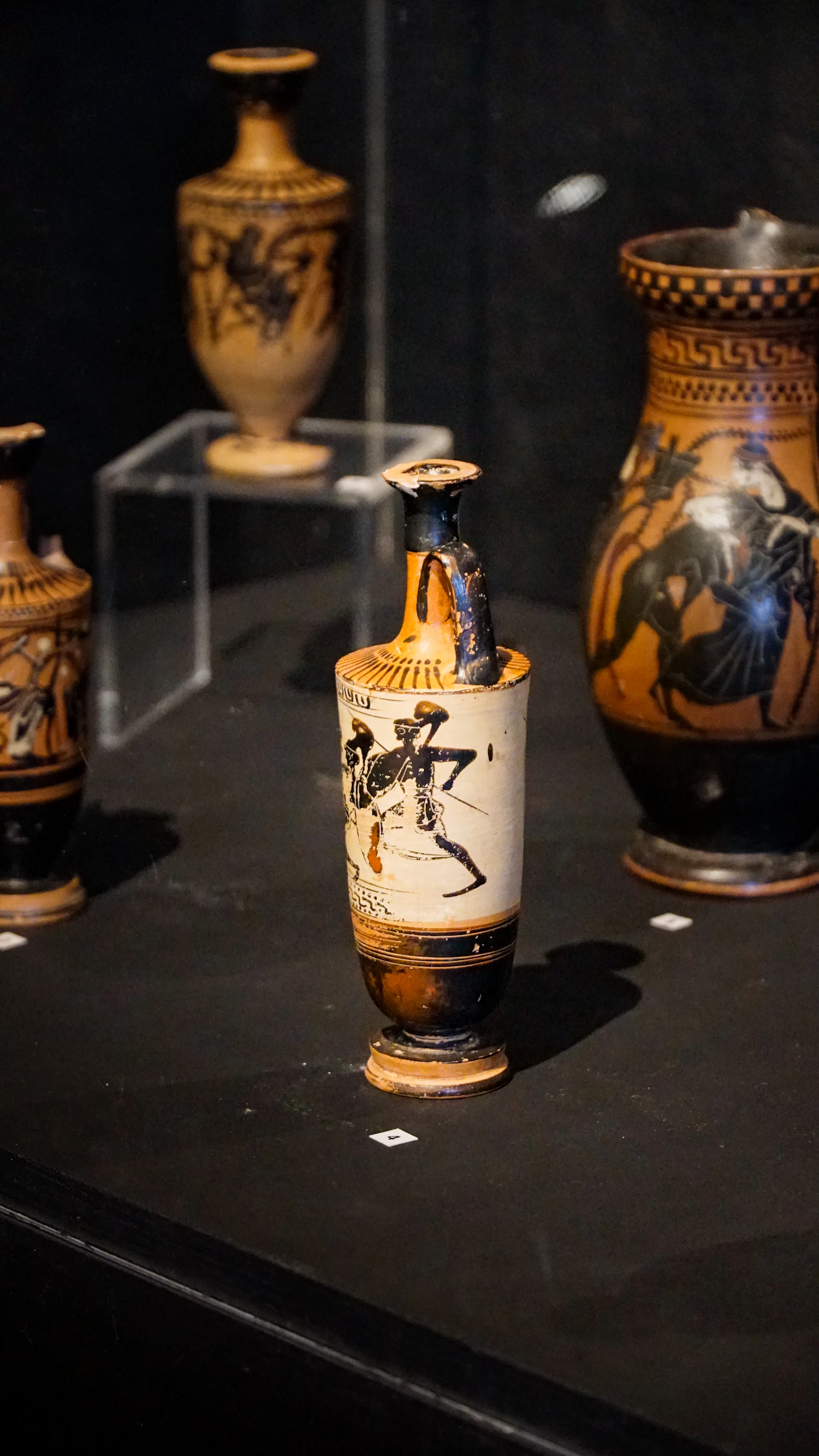 Black-figure pottery standing on a dark plinth under a case light