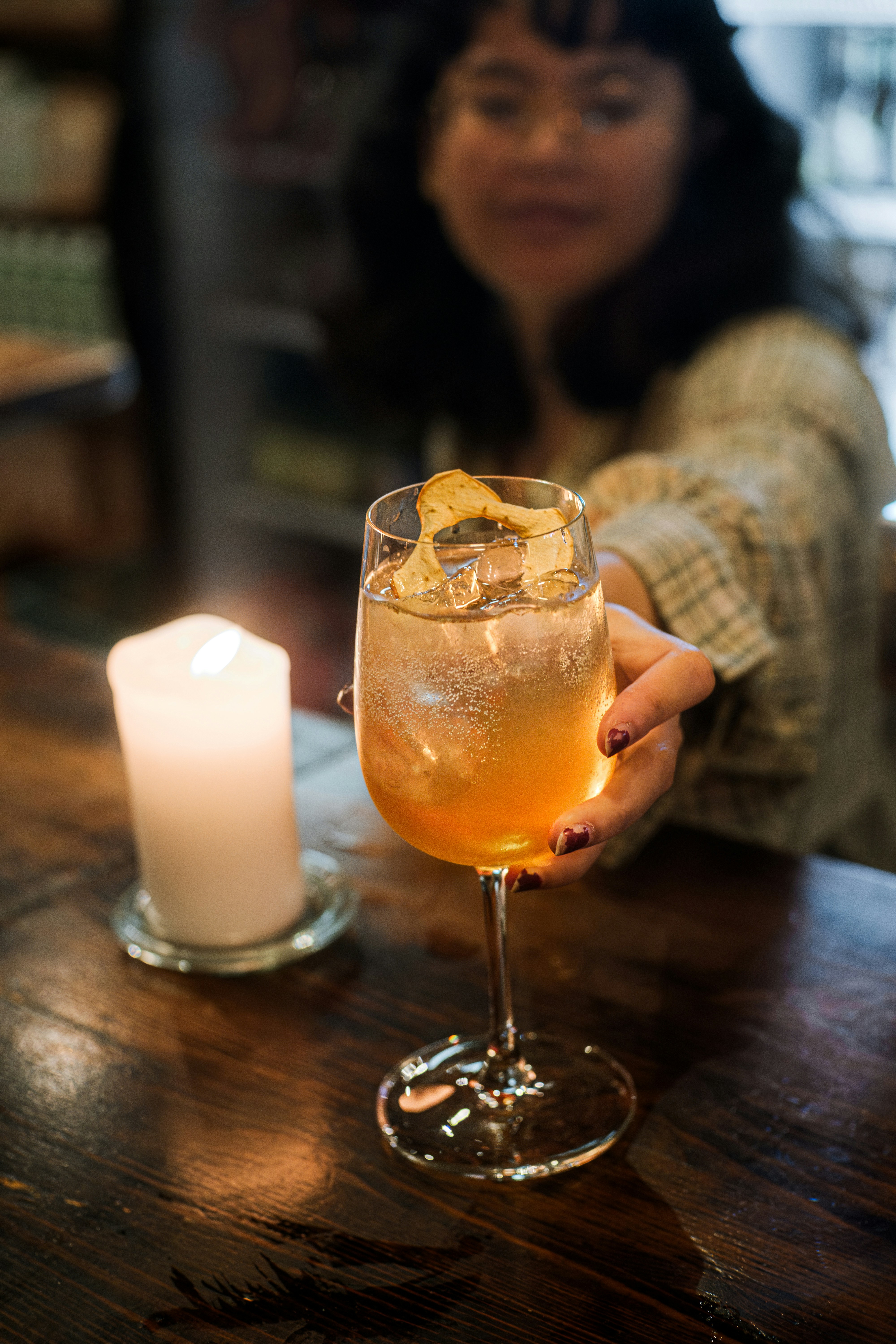 한 손이 촛불 옆에 칵테일을 건넨다.
