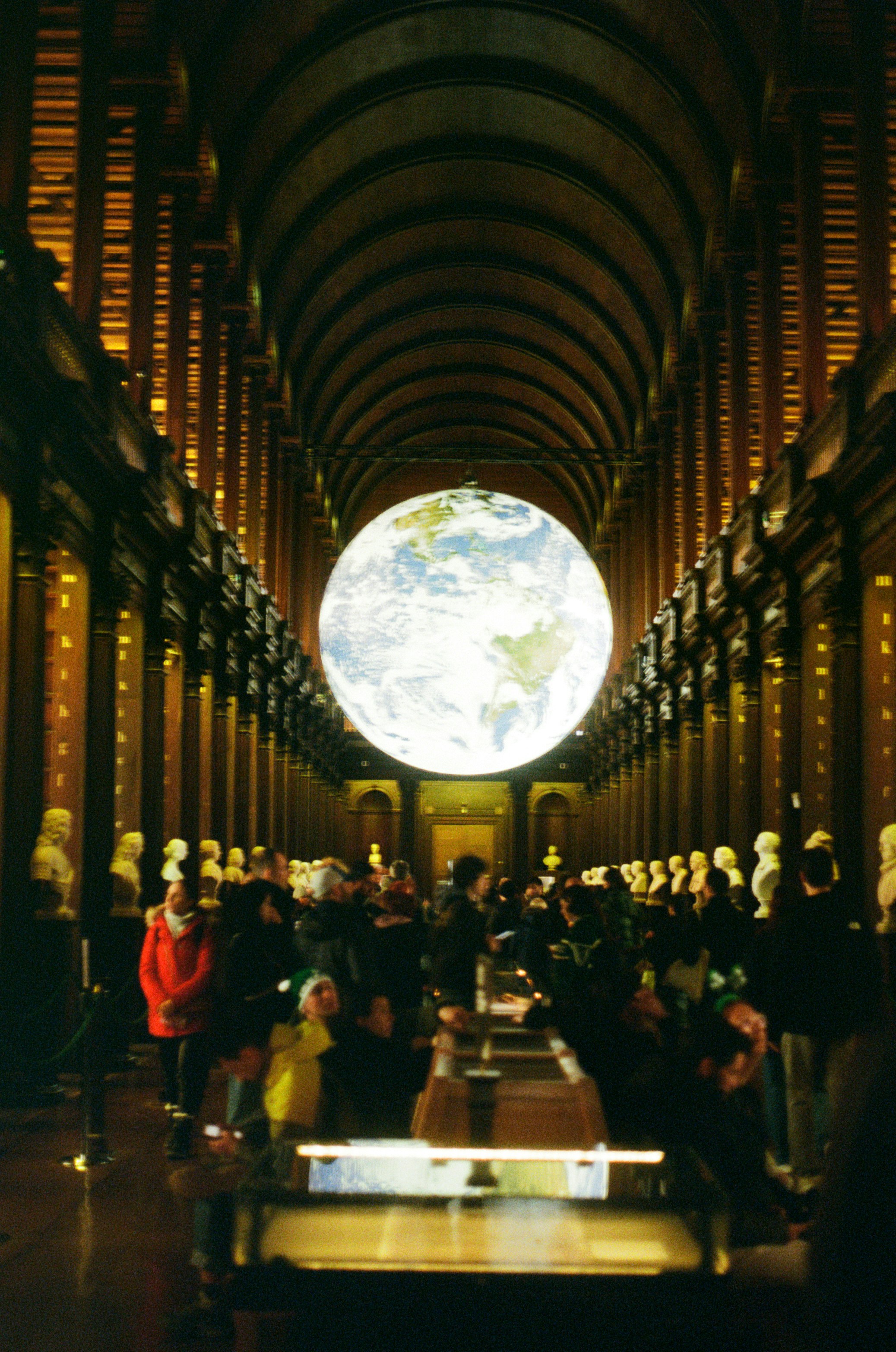 A large globe hangs in a grand library hall.