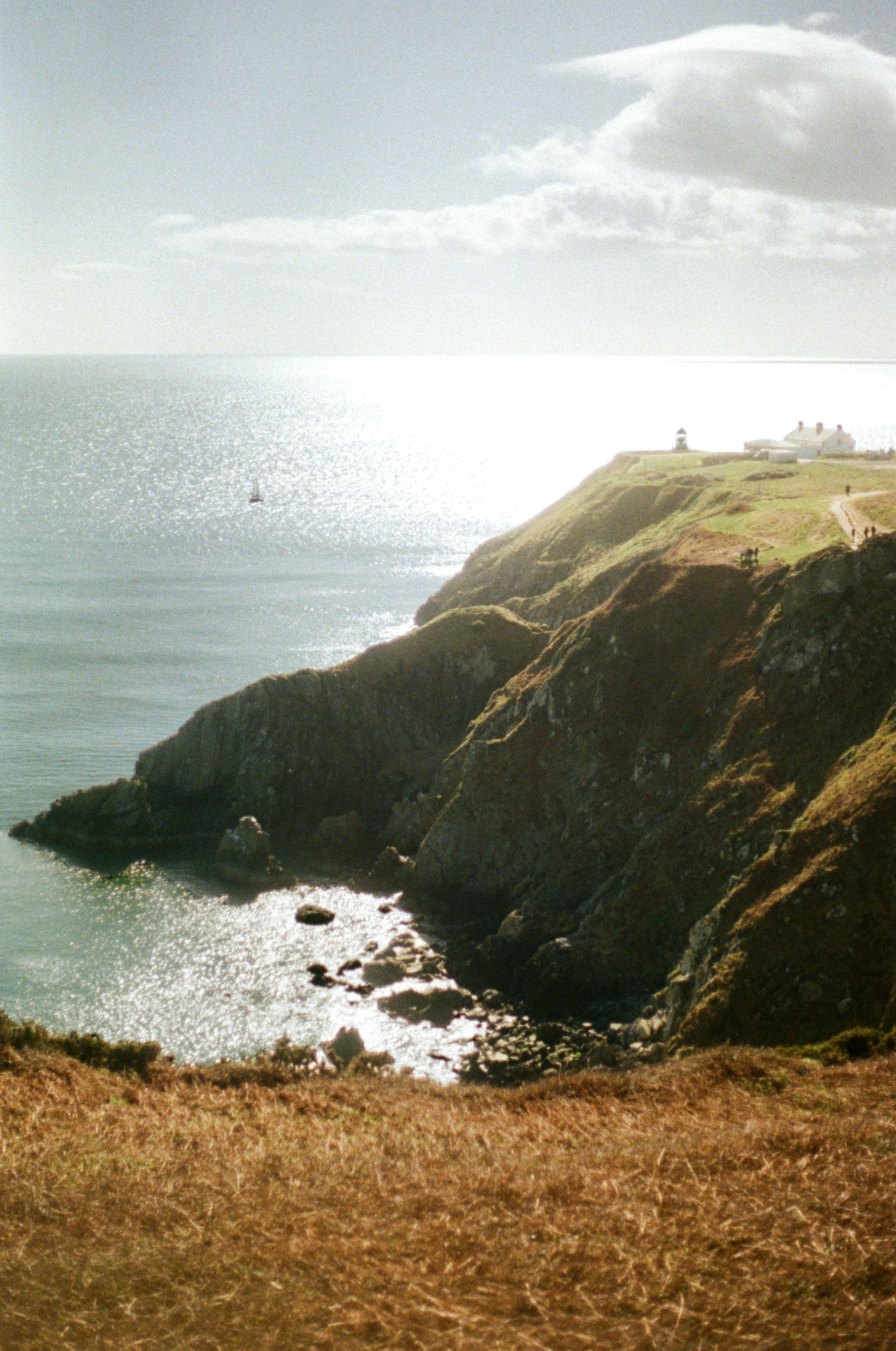Coastal cliffs with a lighthouse under the sun.