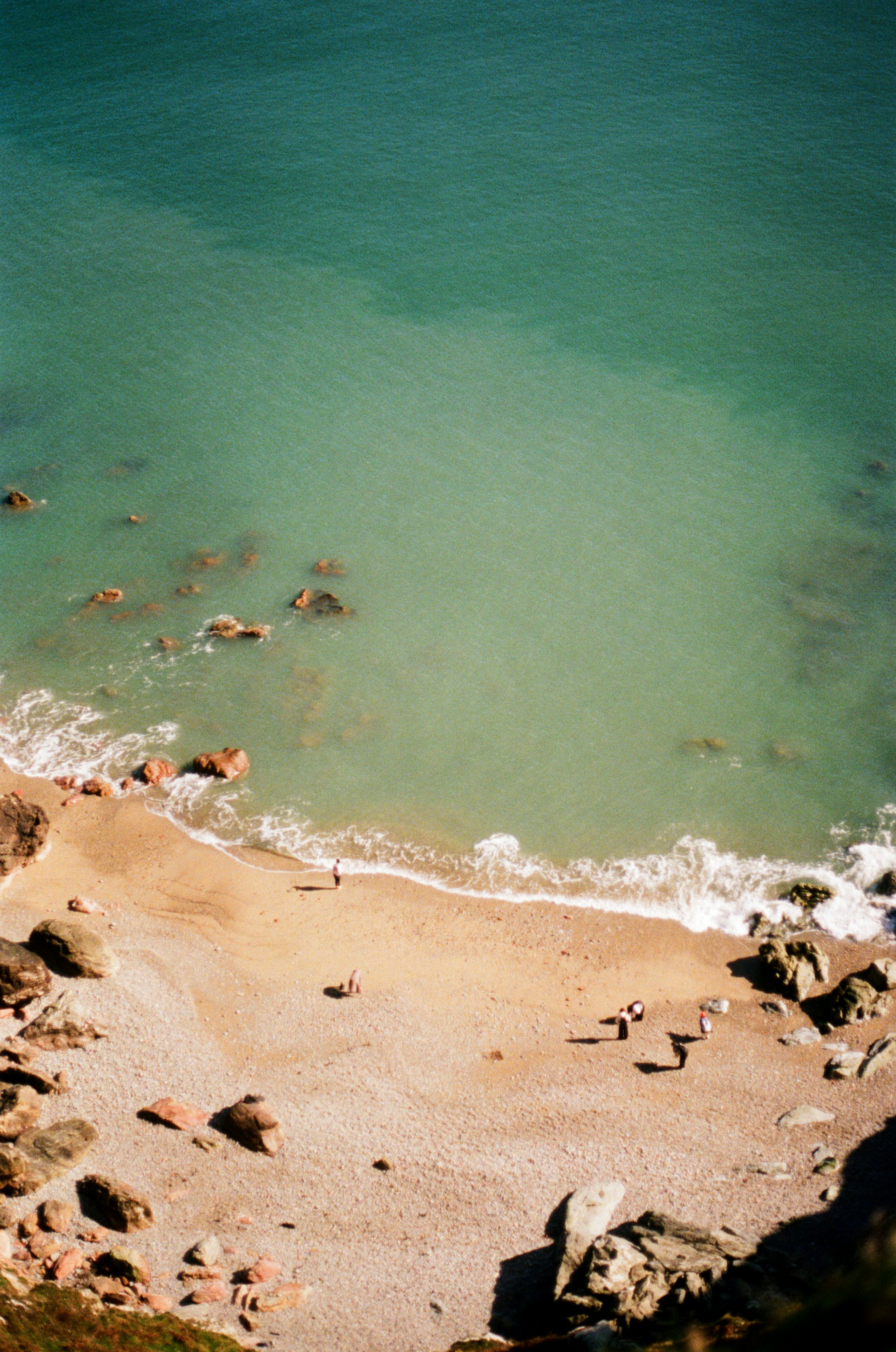 People relaxing on a rocky beach with turquoise water