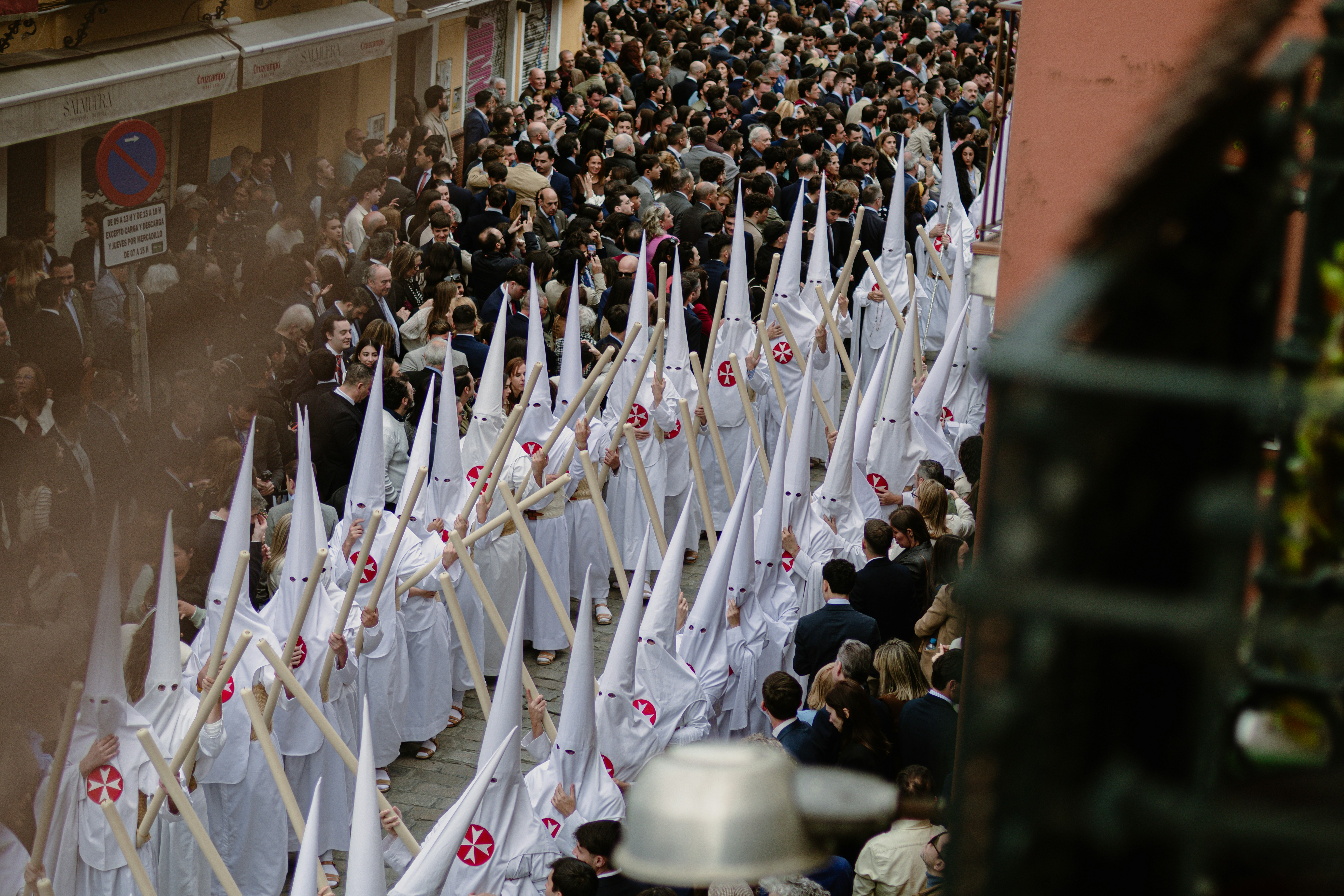 People in white robes and hoods march in a procession.