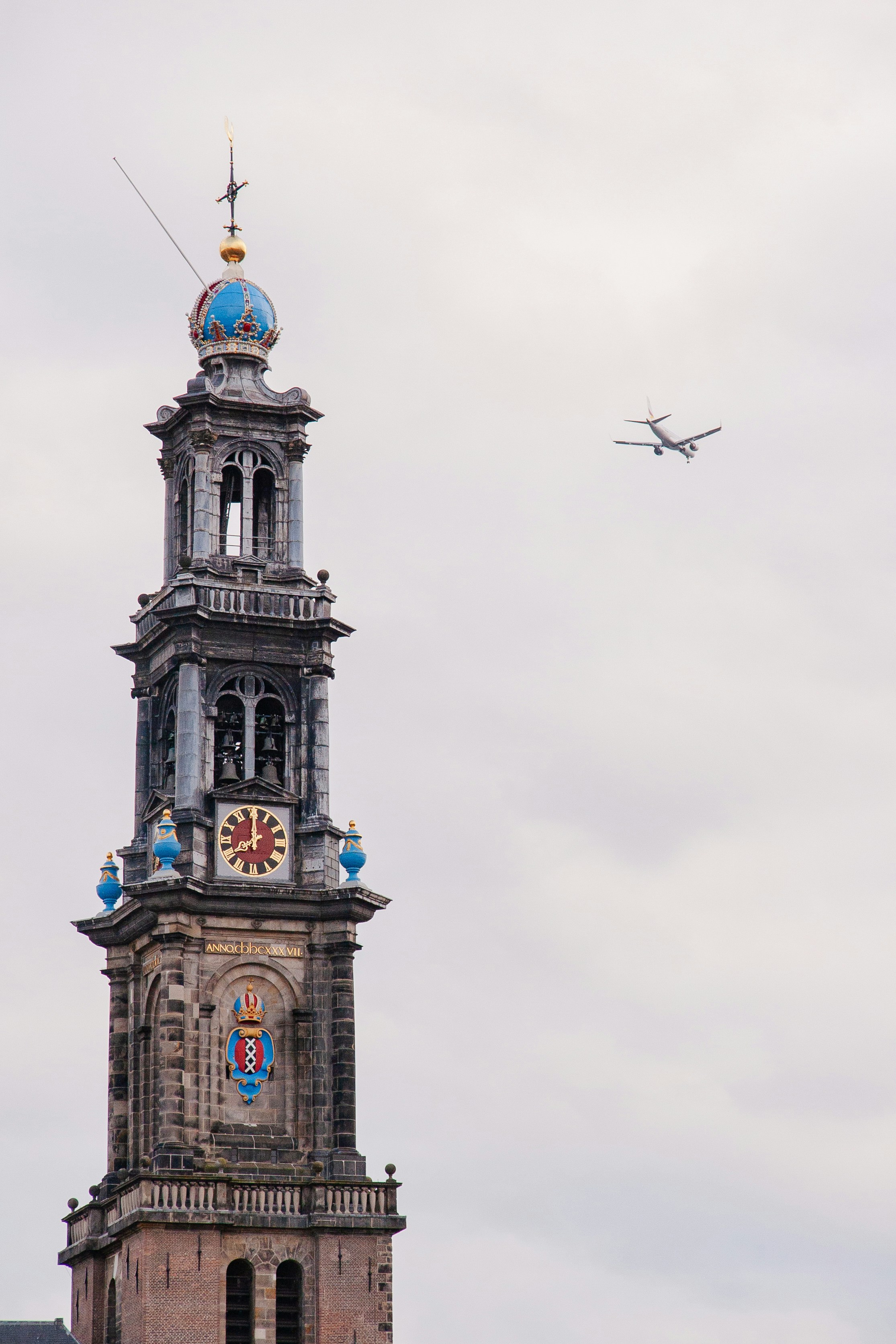 Airplane flies past a historic church tower.